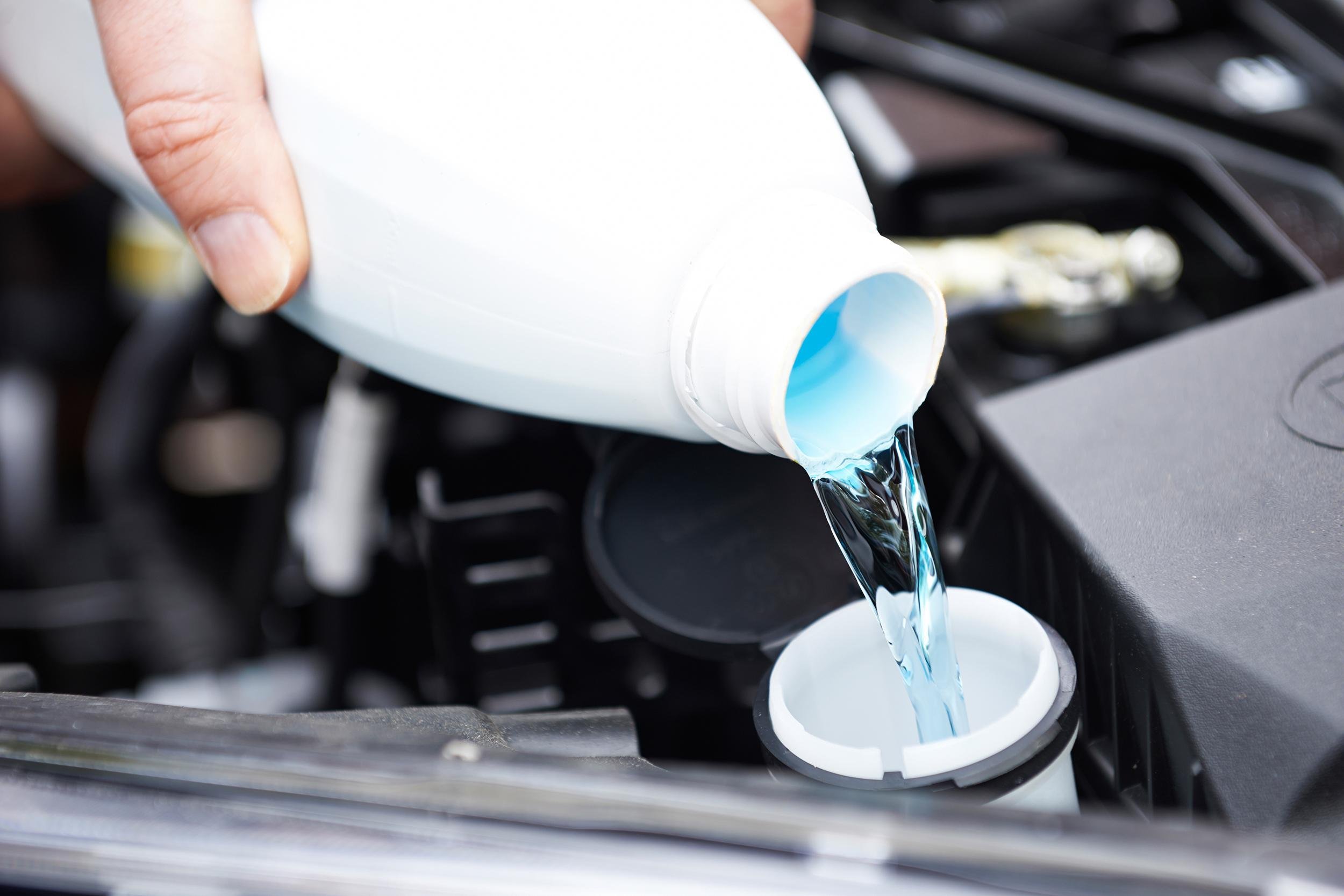 close-up of man topping up windshield washer fluid in car
