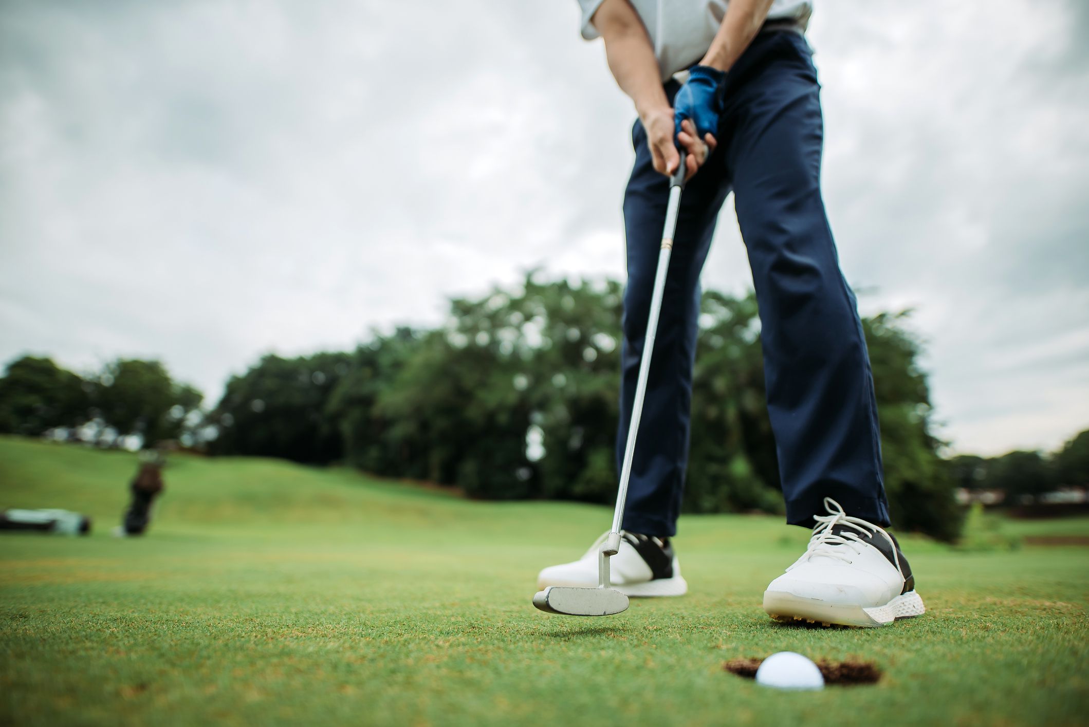 male golfer tapping the golf ball into a hole at golf course