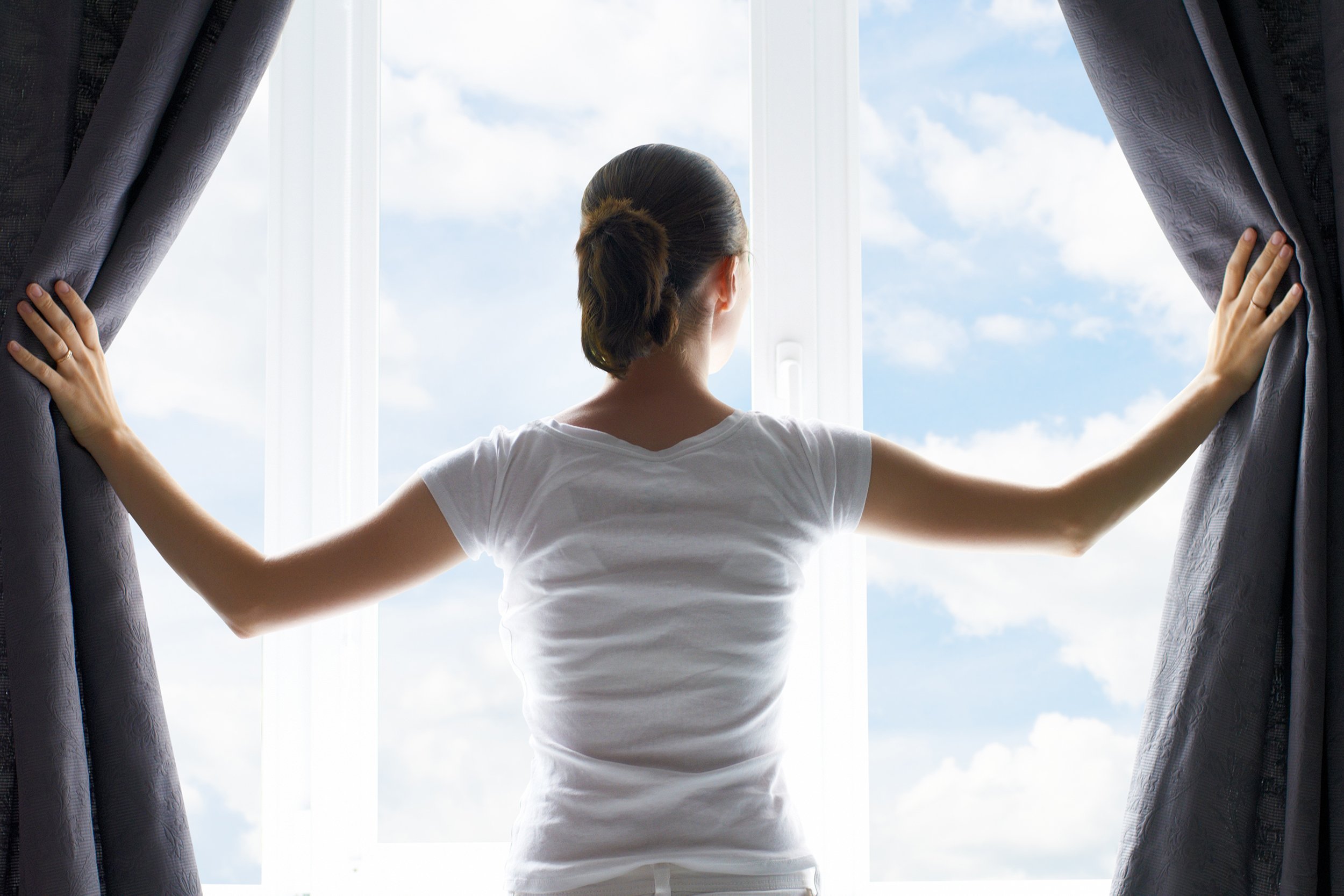 woman opening curtains