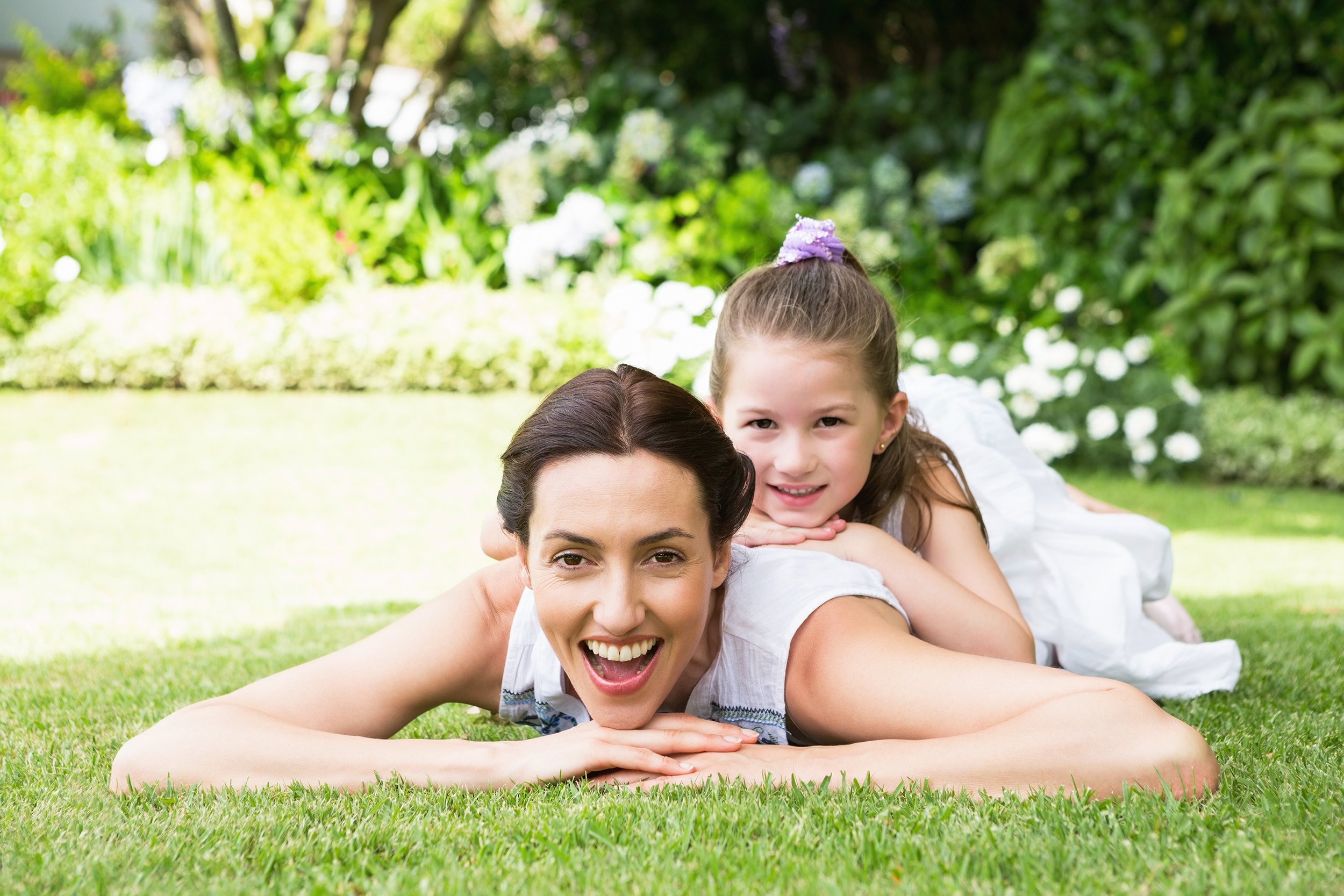 mother and daughter laying on grass in yard