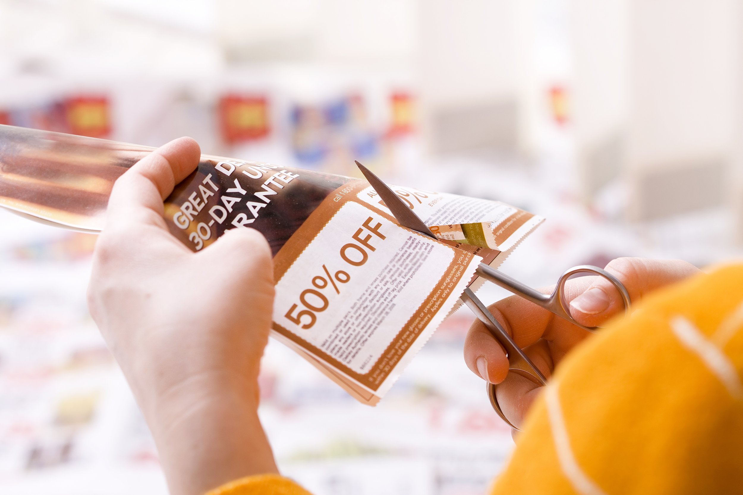 woman cutting paper coupon
