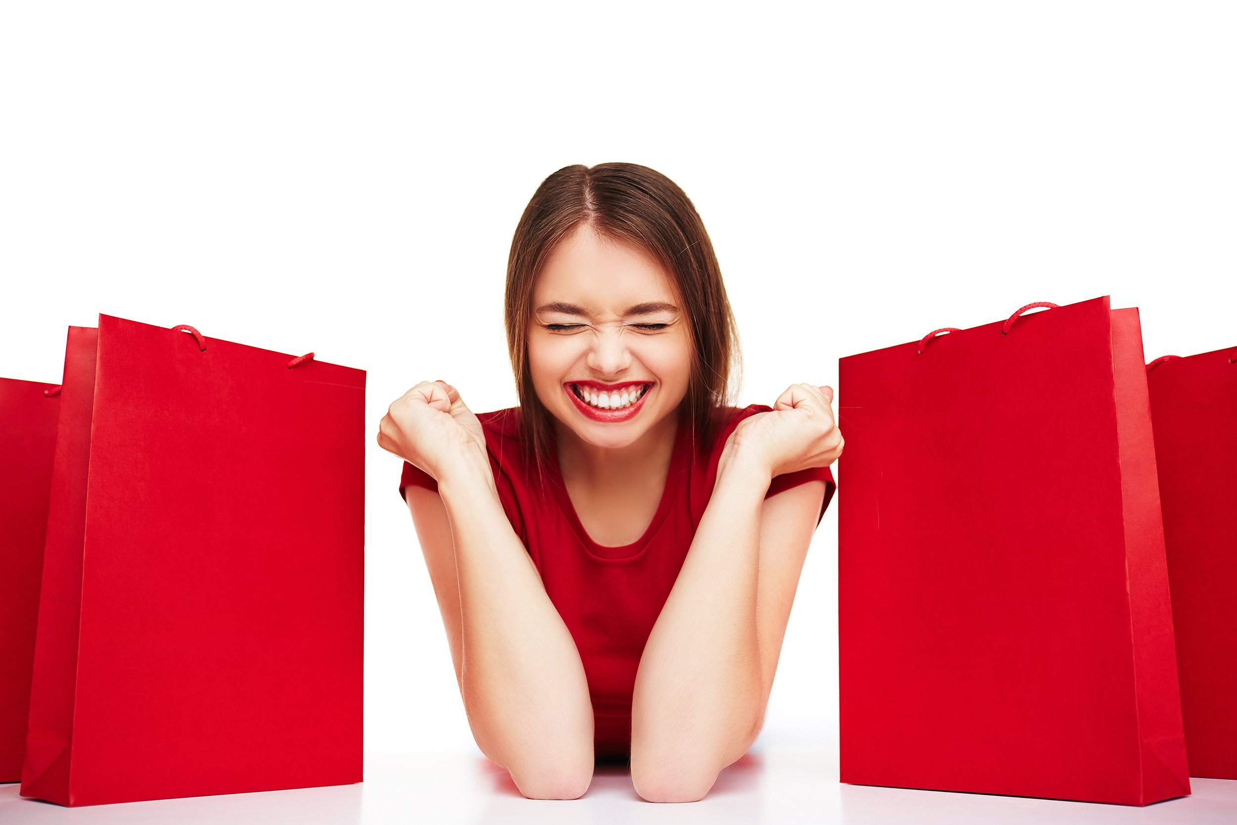 joyful woman with expression of triumph lying between red bags