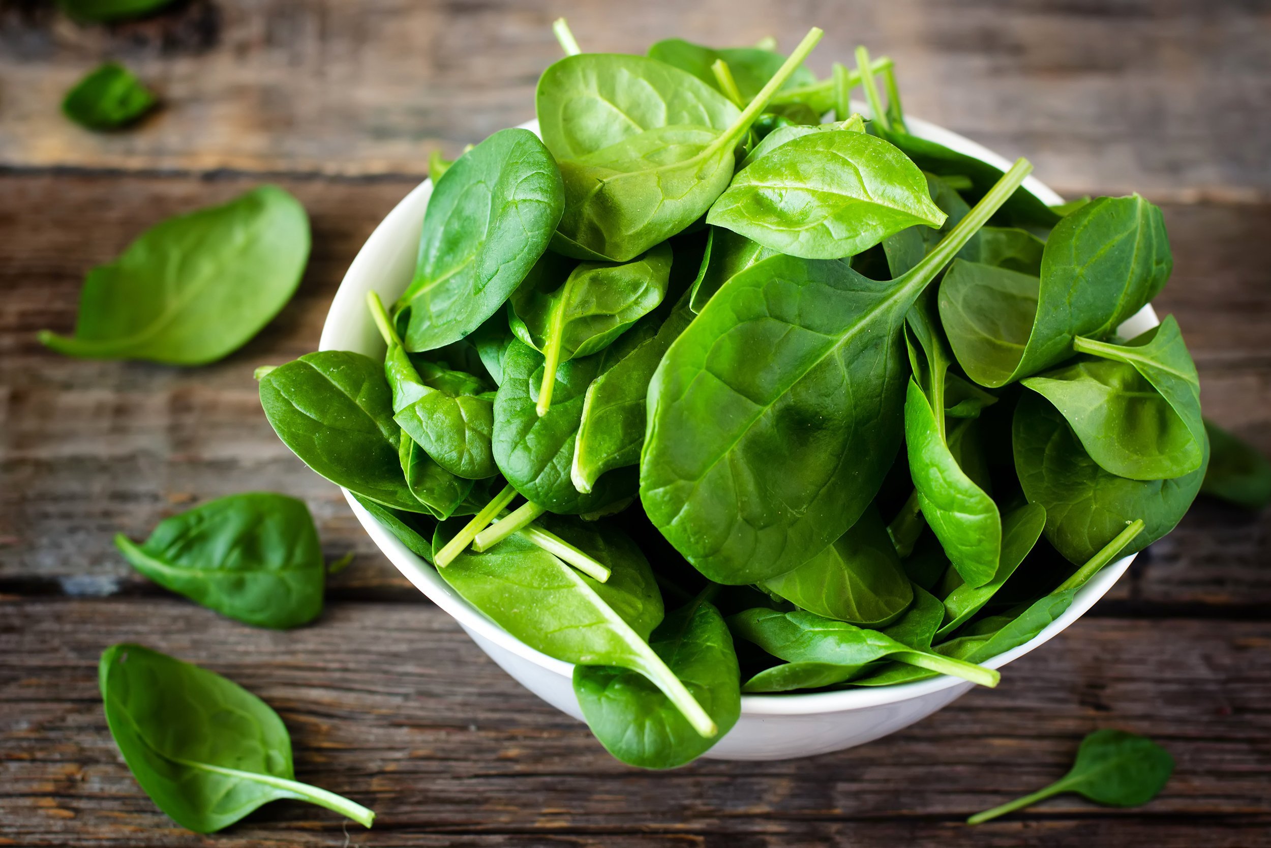 spinach in the bowl on the dark wood background