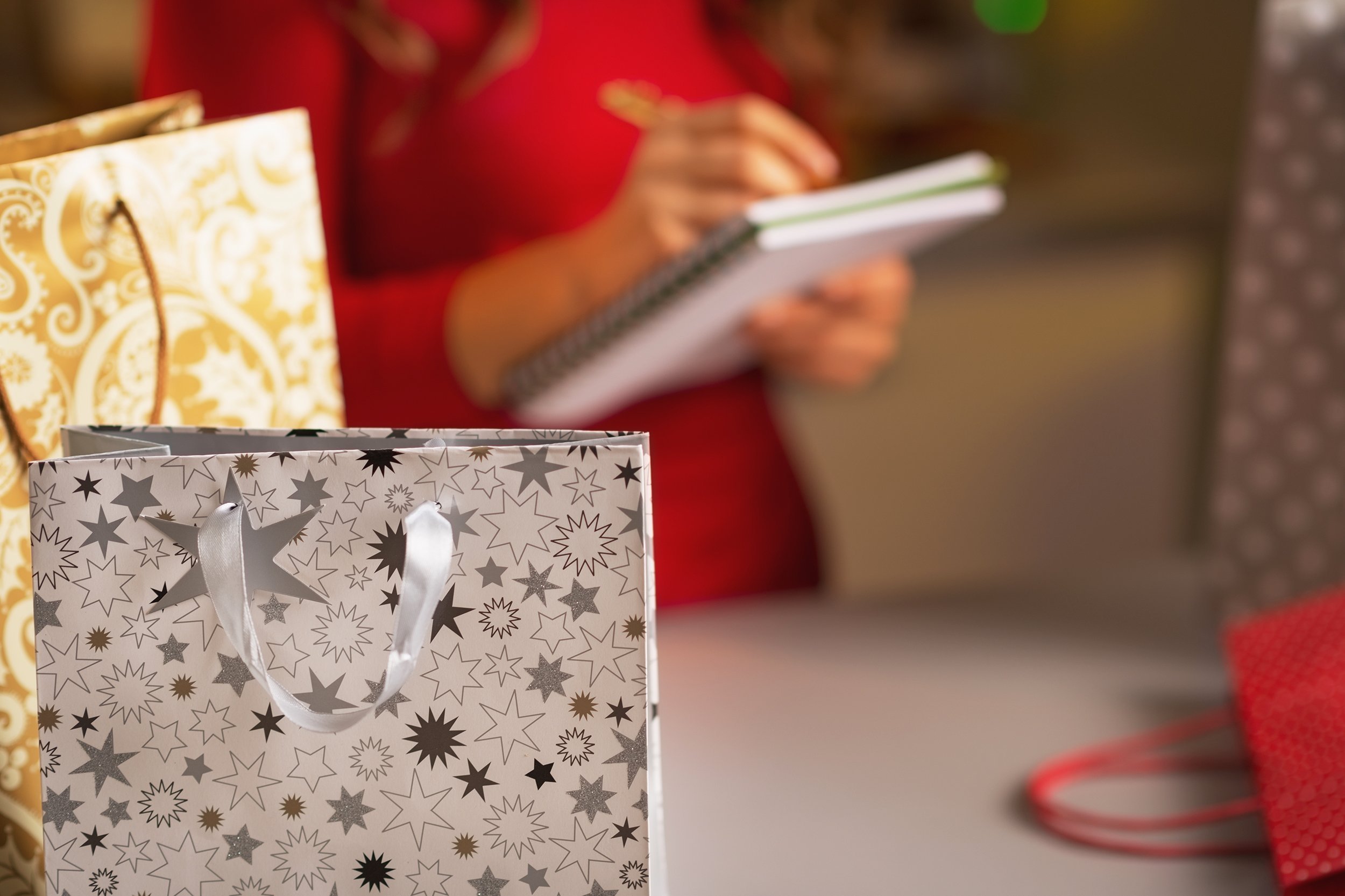 christmas shopping bag and woman checking list of presents