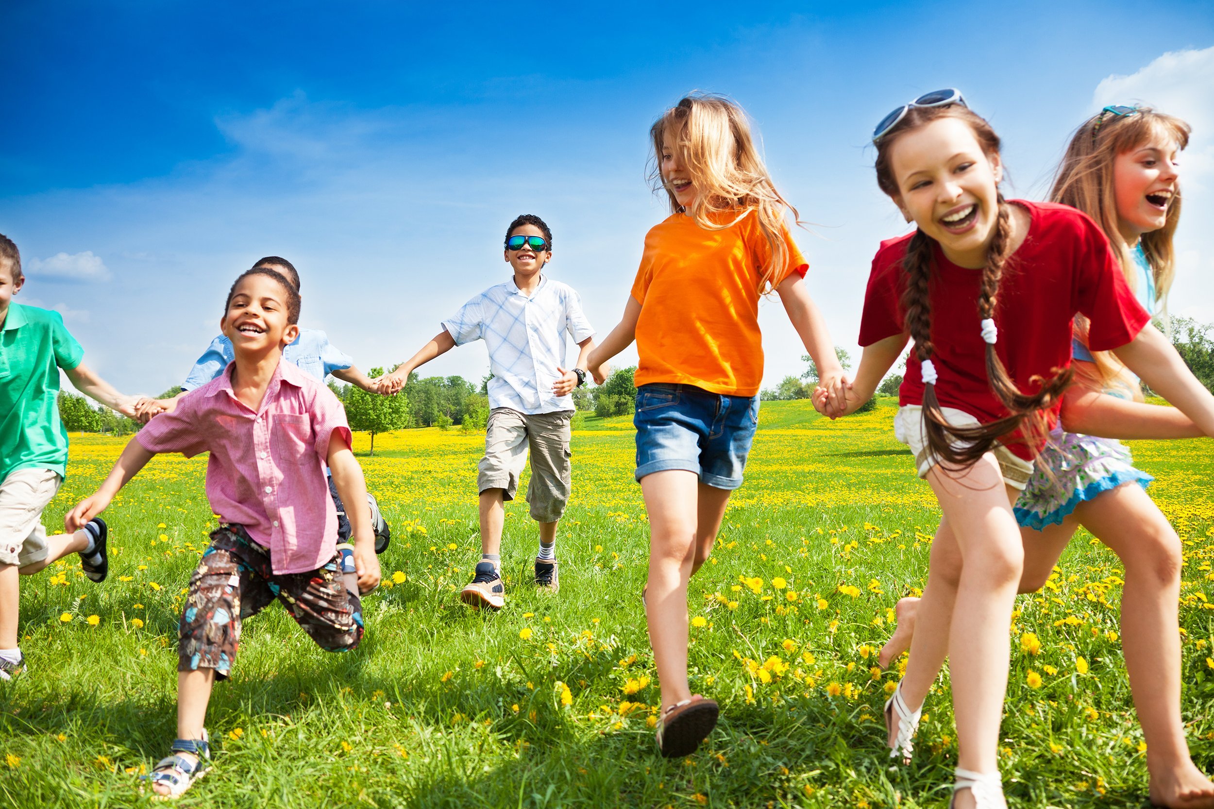 large group of children running in the dandelion spring field