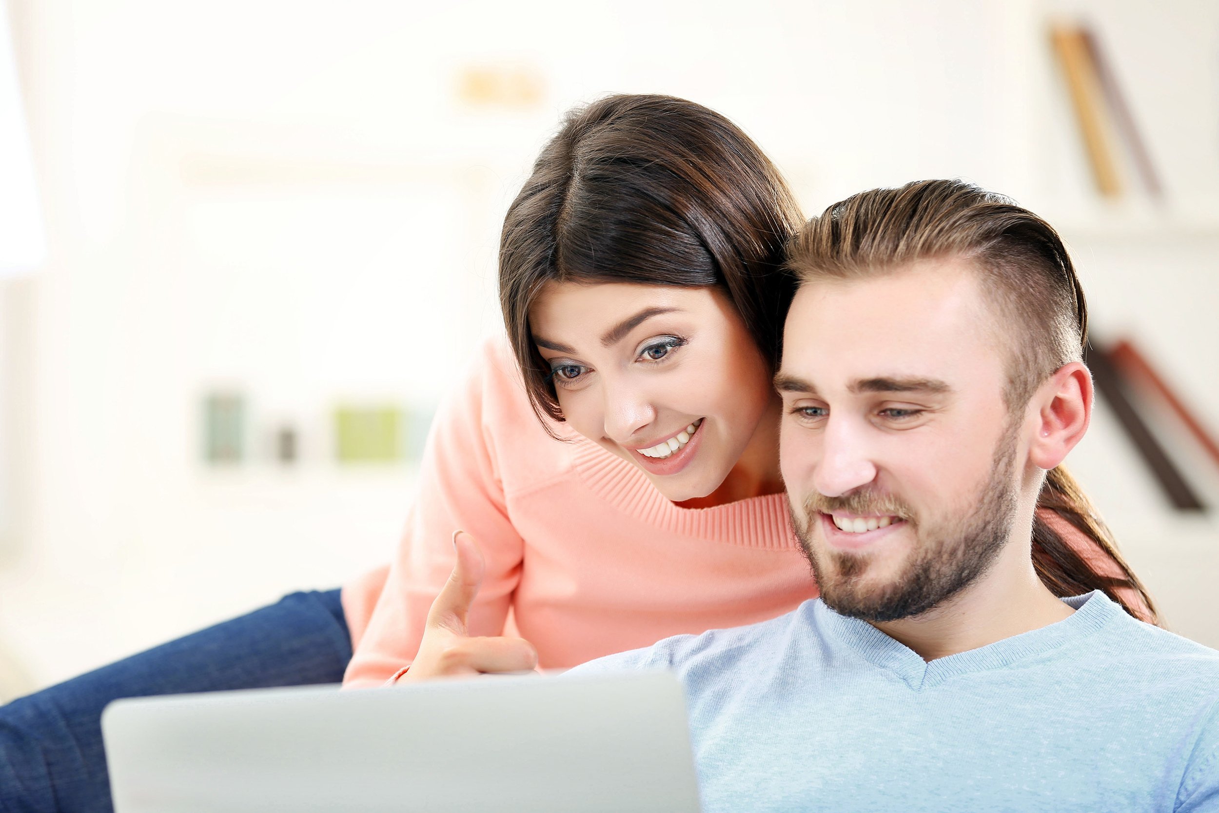 happy couple looking at a laptop in a room