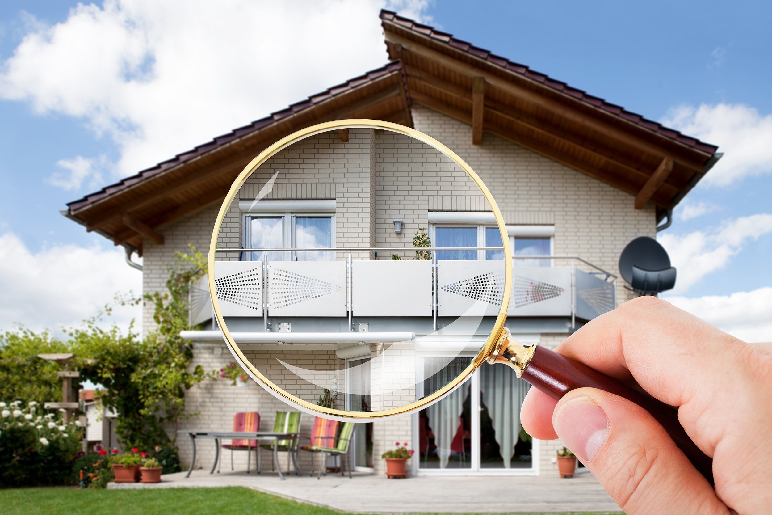hand with magnifying glass over house
