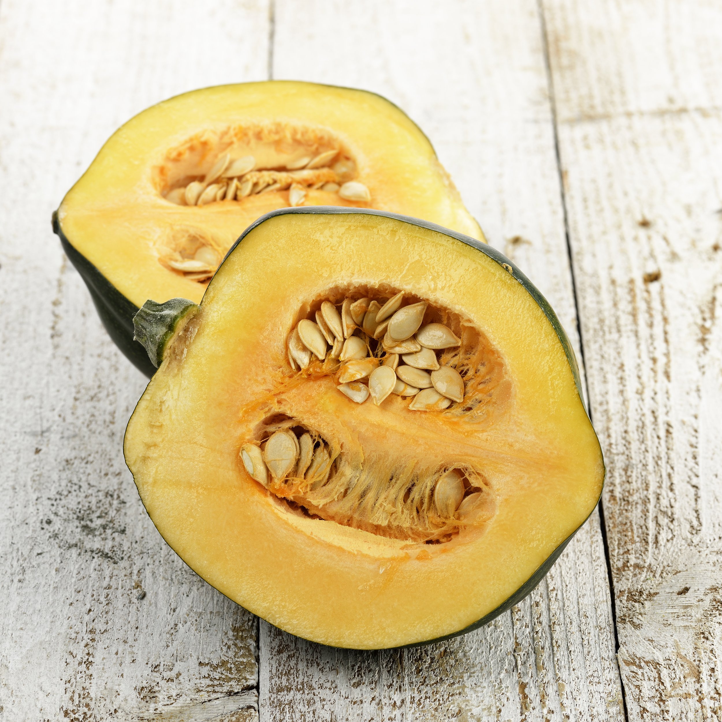 two halves of acorn squash on a wooden board