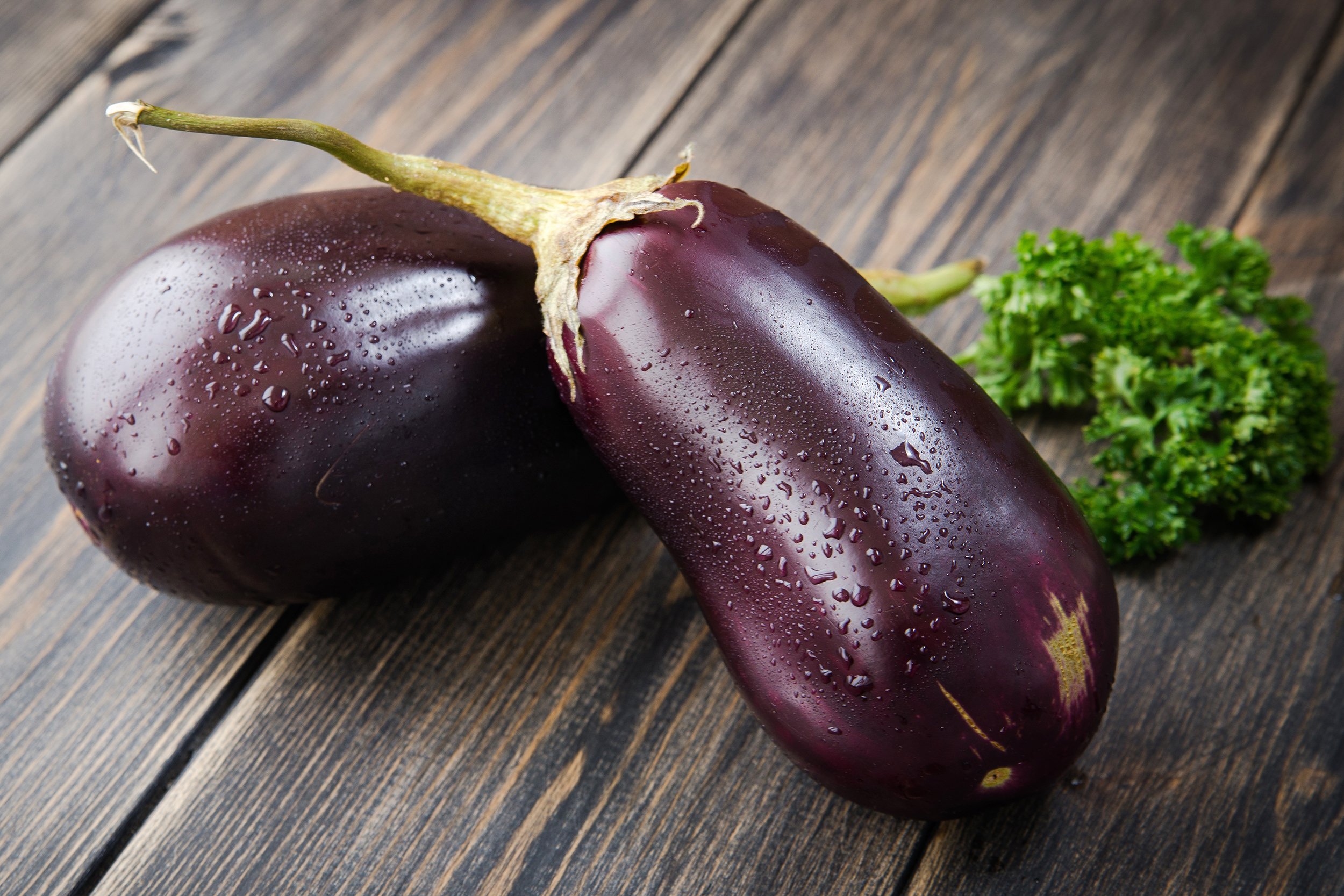 fresh healthy eggplants on dark wooden background