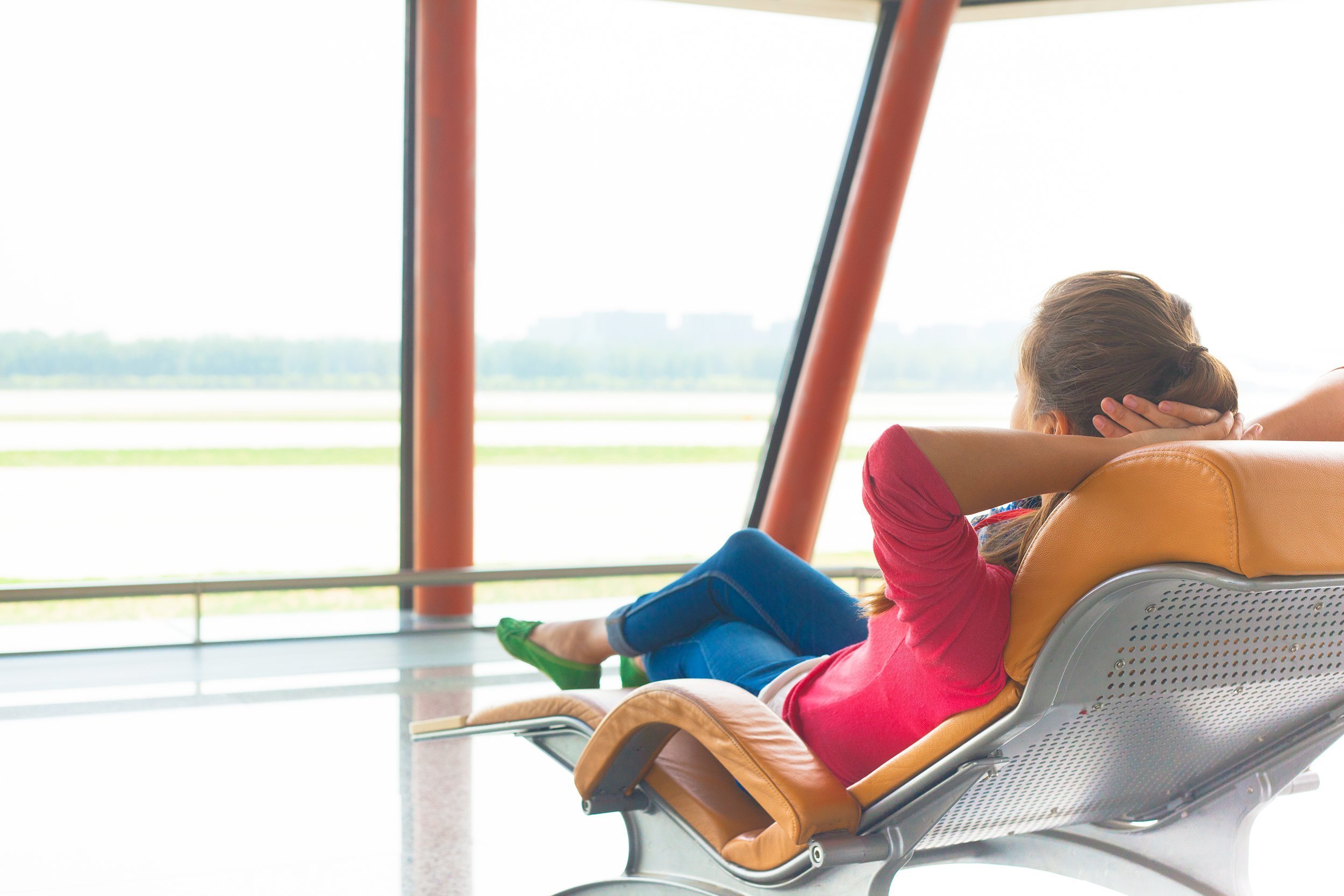 woman waiting for her flight at the airport on lounge chair