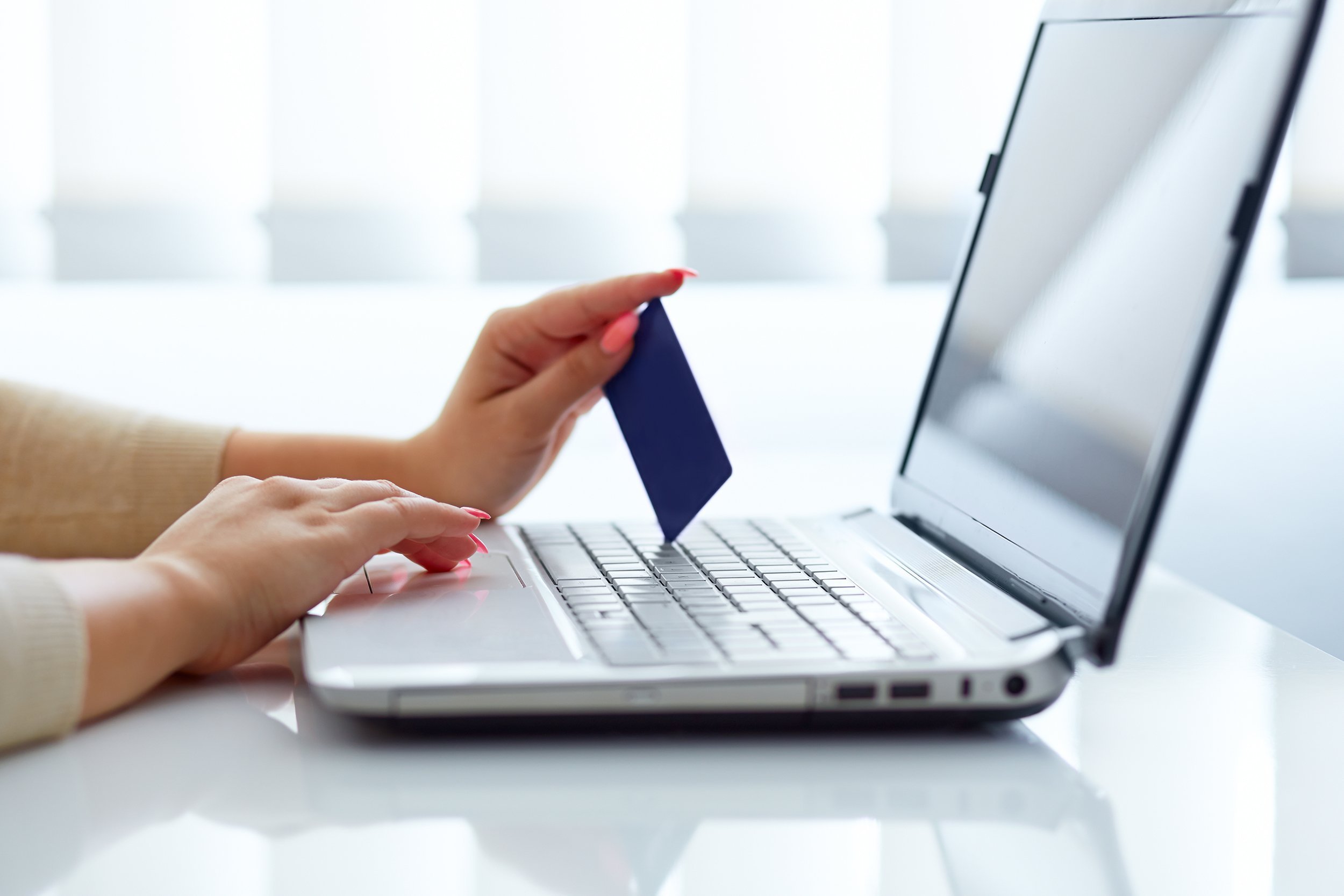 female hand inserts data into the laptop and holding credit card