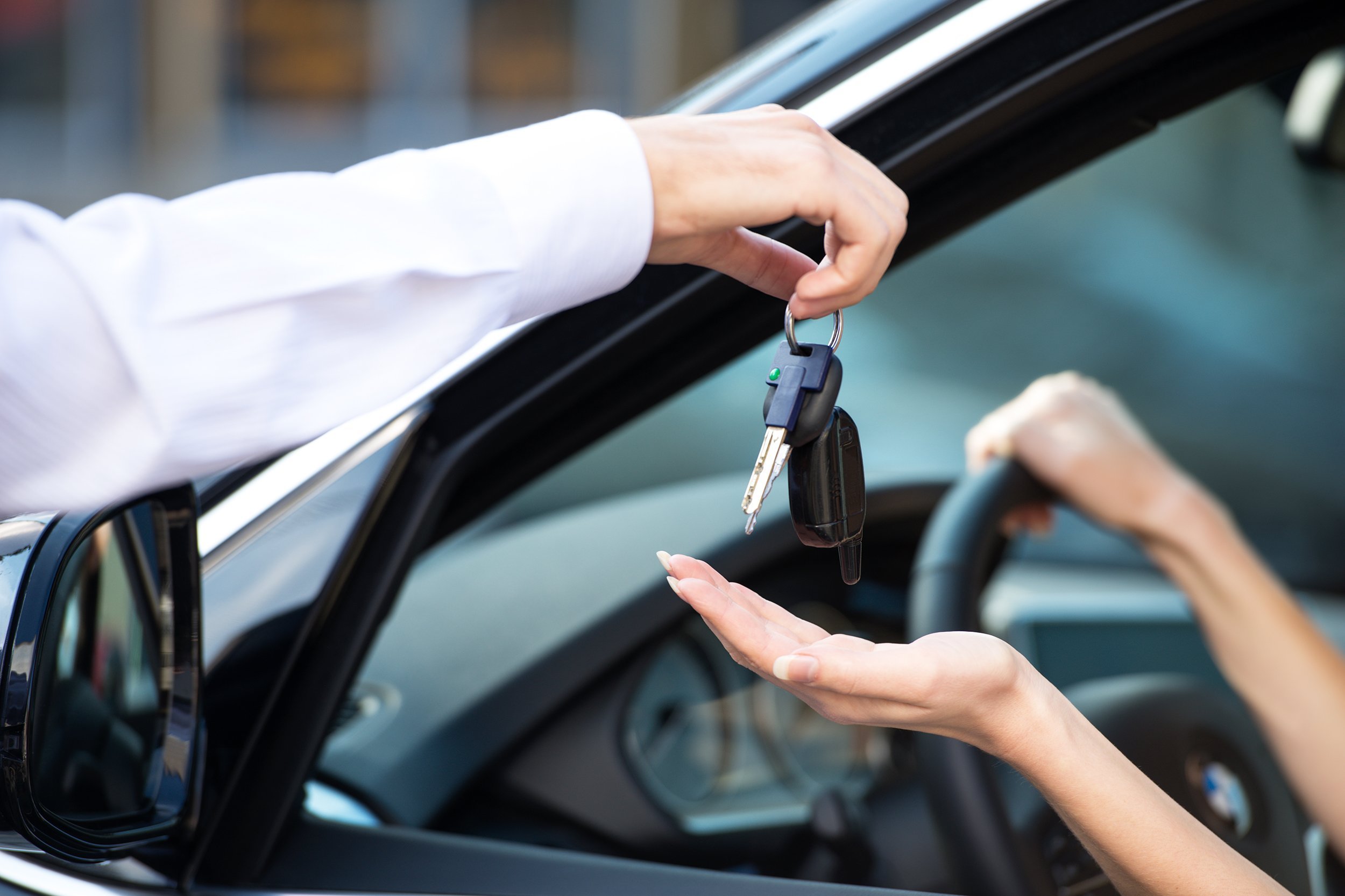 close up of car dealer giving keys of a new car to woman