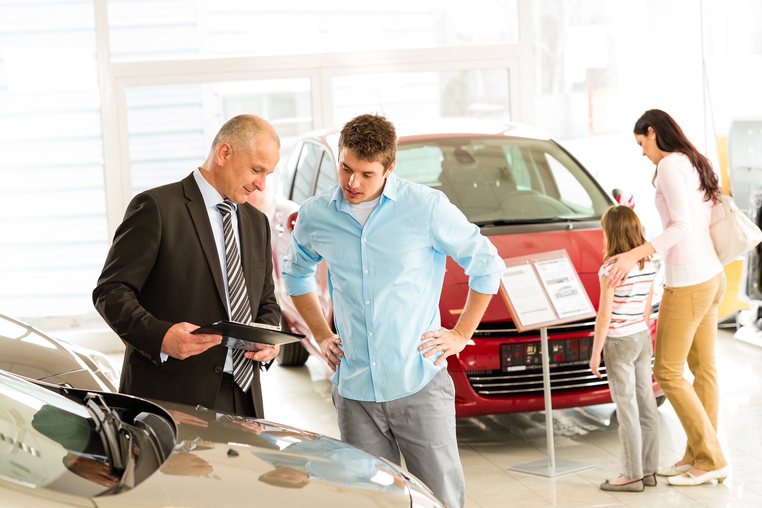 car agent showing vehicle to young family