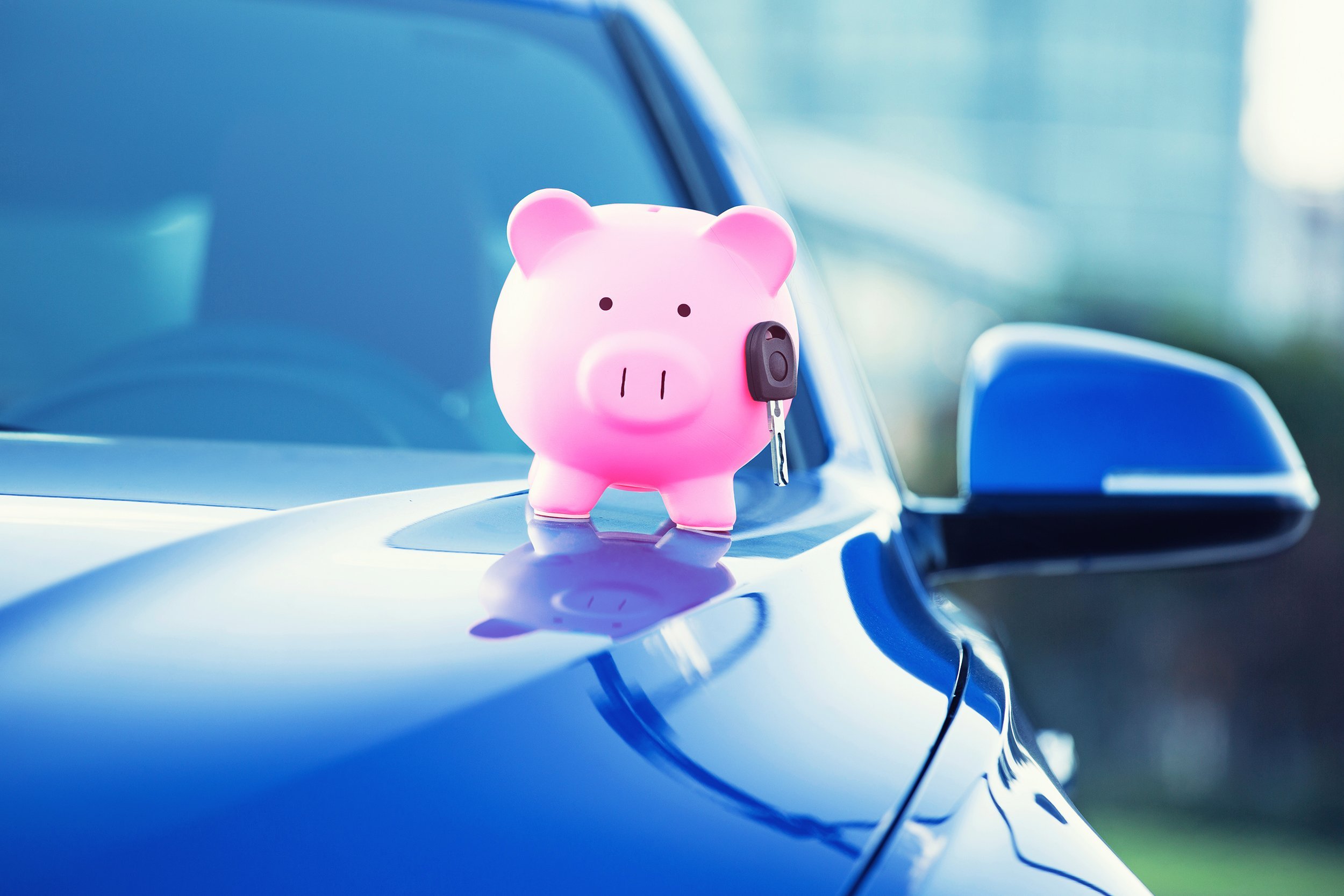 piggy bank with key on hood of car