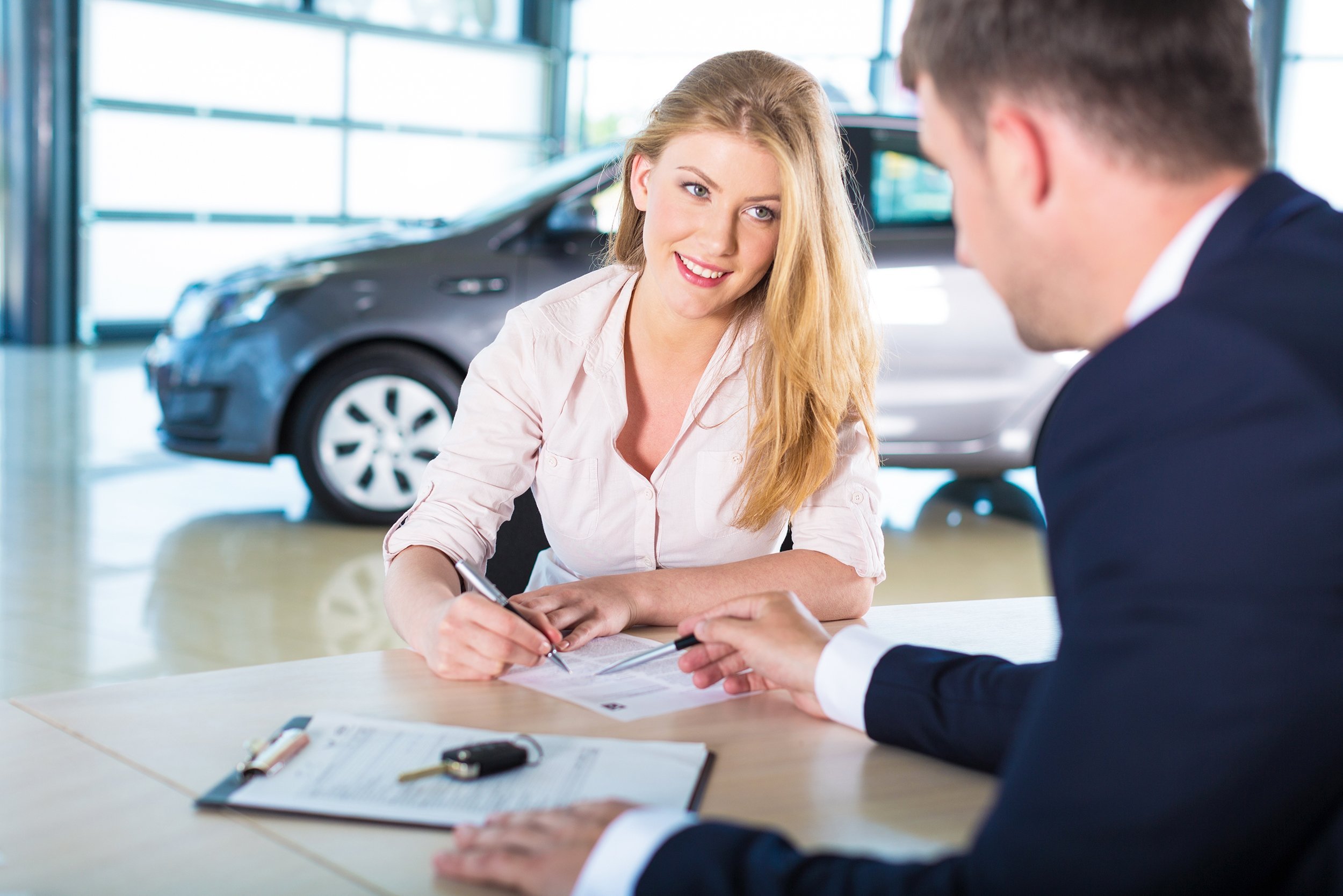 customer at car dealership signing contract