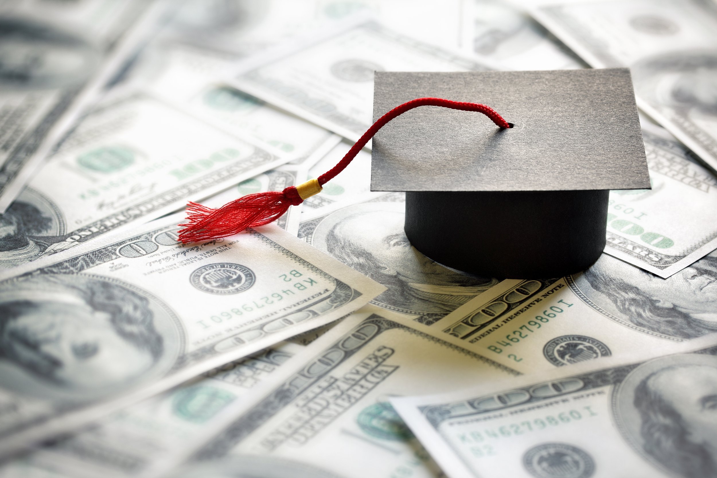 graduation mortar board cap on one hundred dollar bill