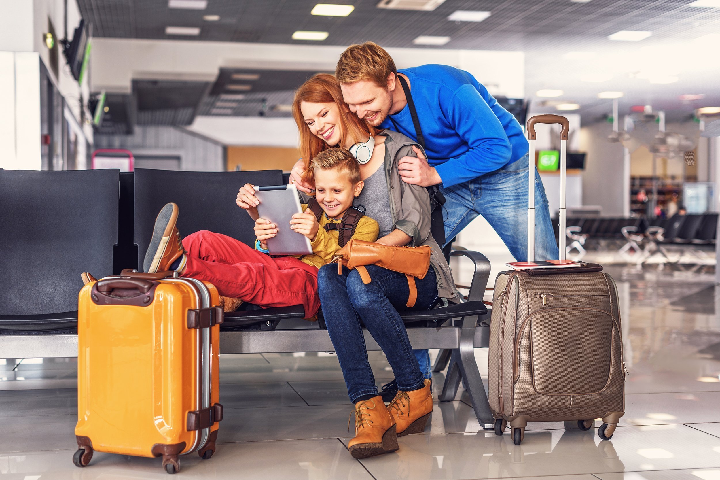 smiling happy family doing holiday trip and looking map on digital tablet at airport