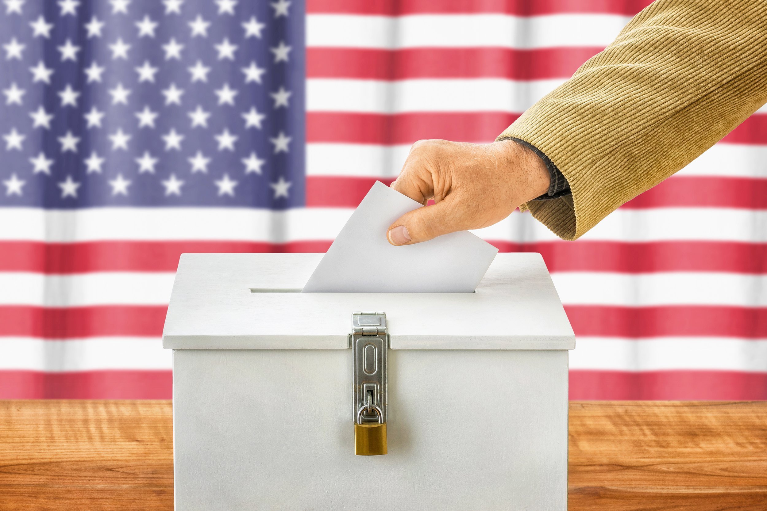 man putting a ballot into a voting box