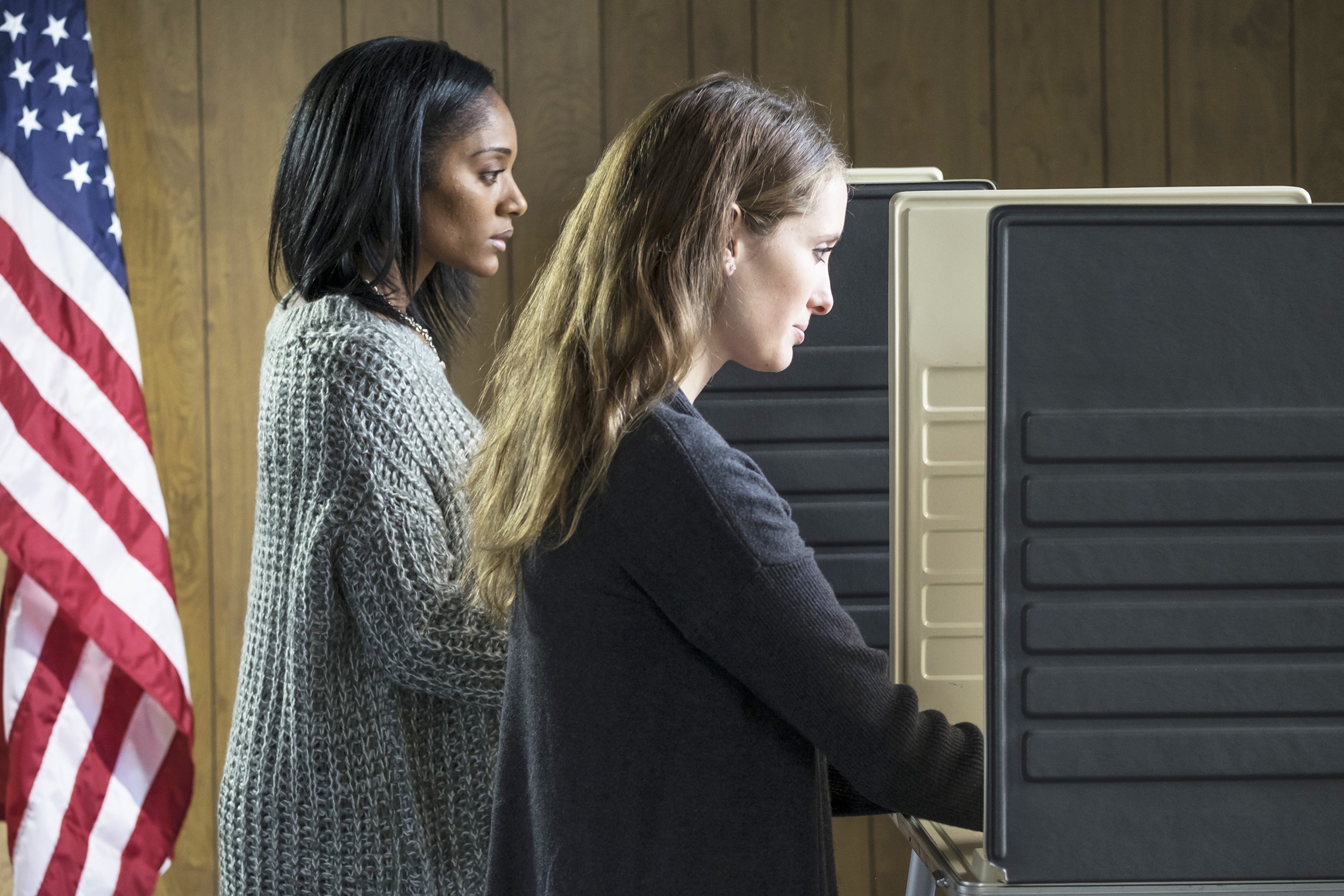 two young adult women voting in a voting booth