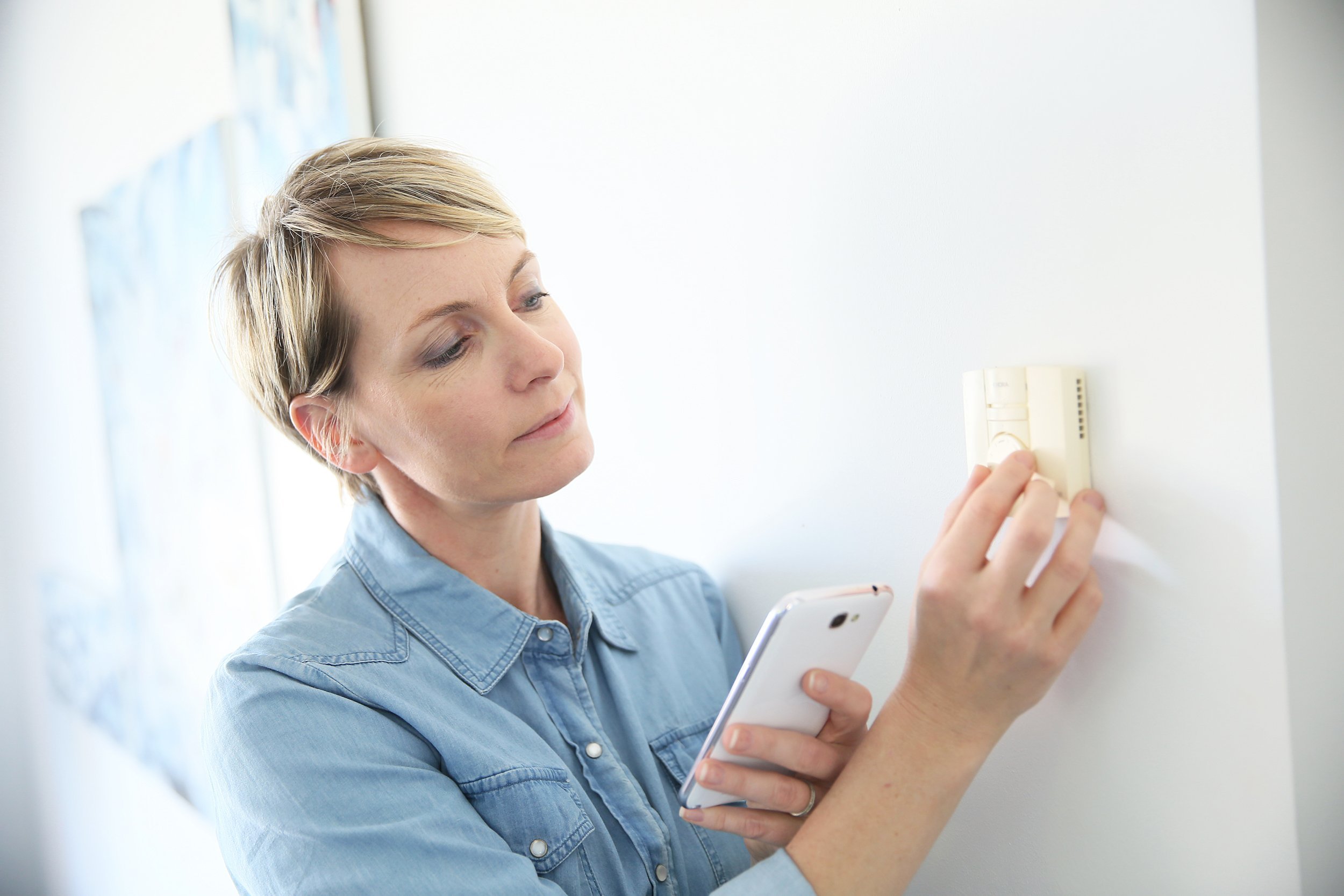 woman programming indoor temperature with smartphone application