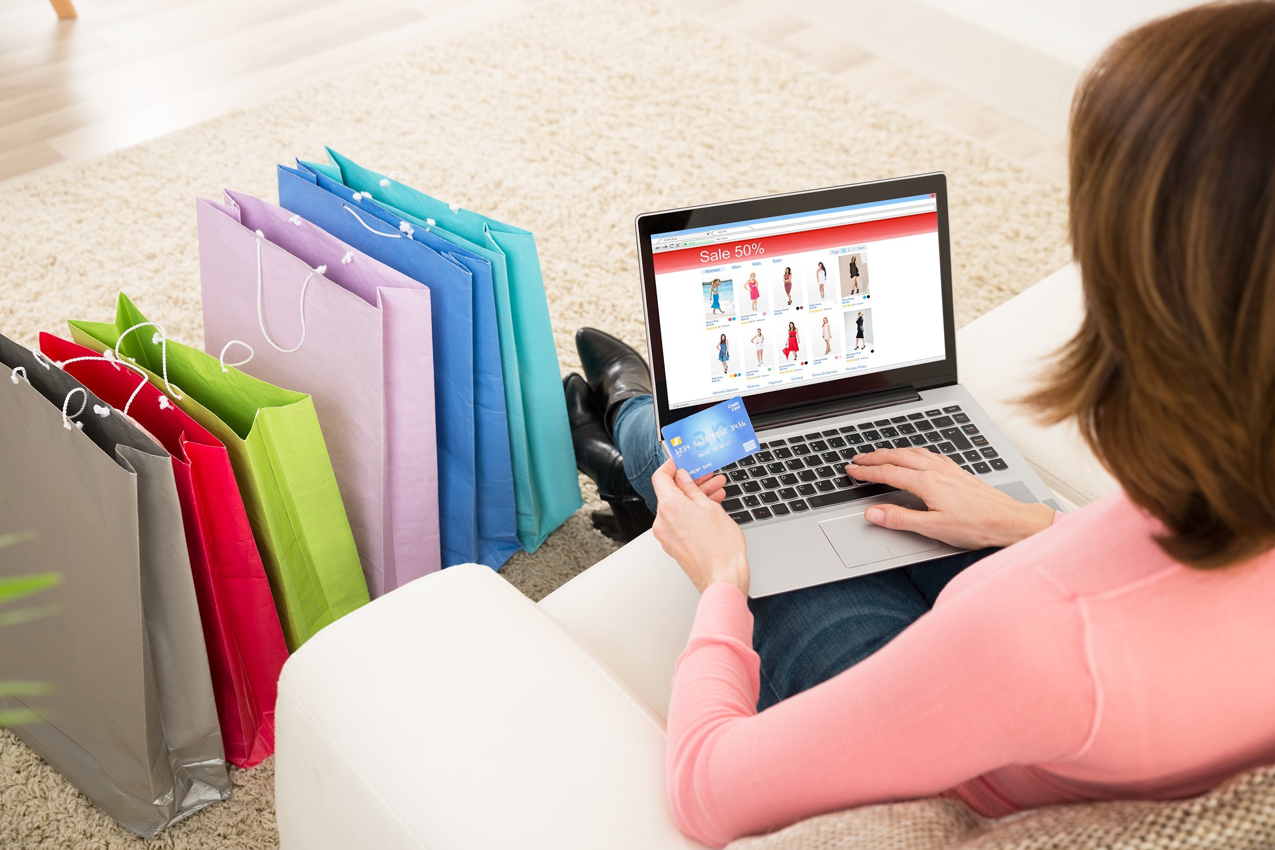 young woman on sofa shopping online with credit card