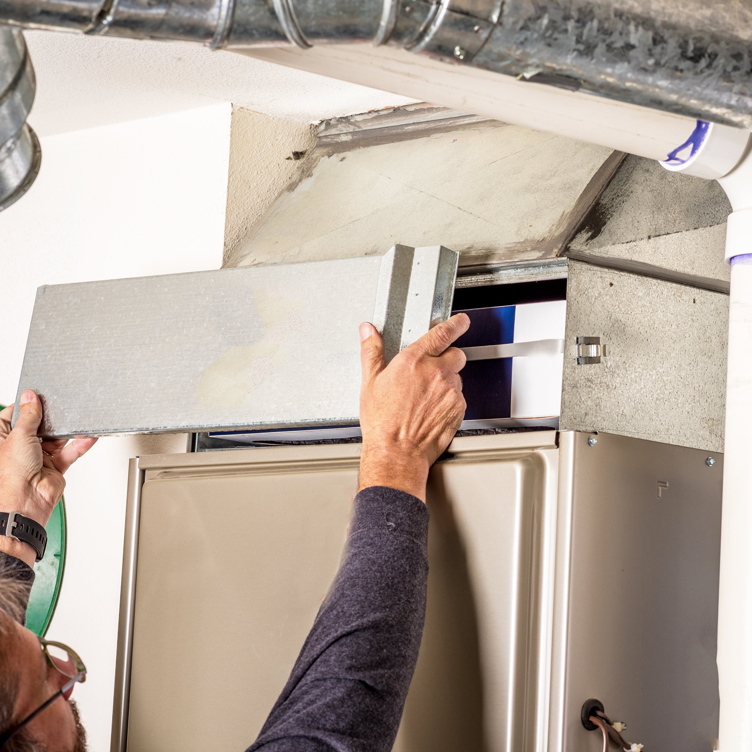 man removes the furnace filter cover to inspection