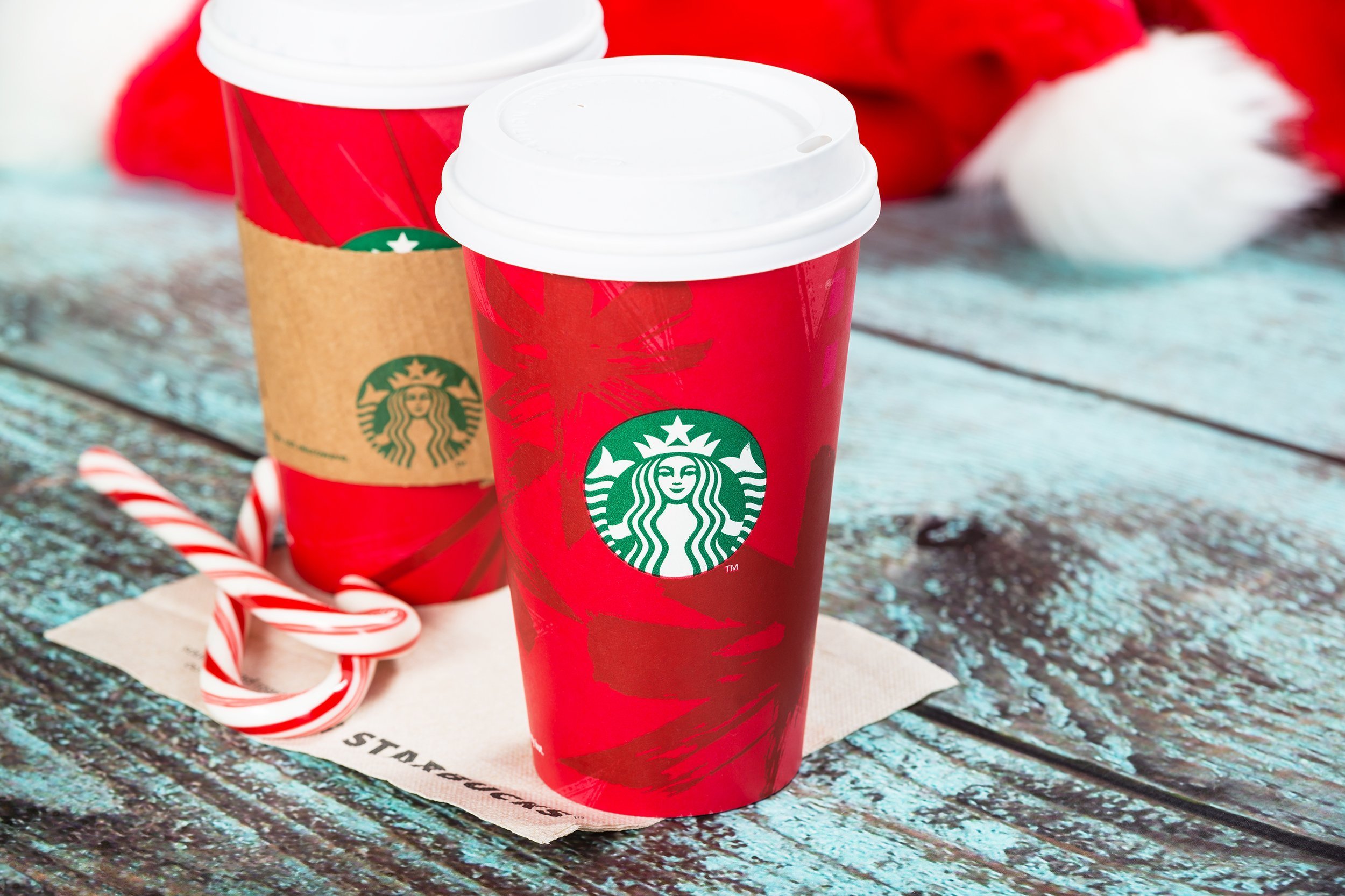 two cups of cup of Starbucks holiday beverages on blue wooden table