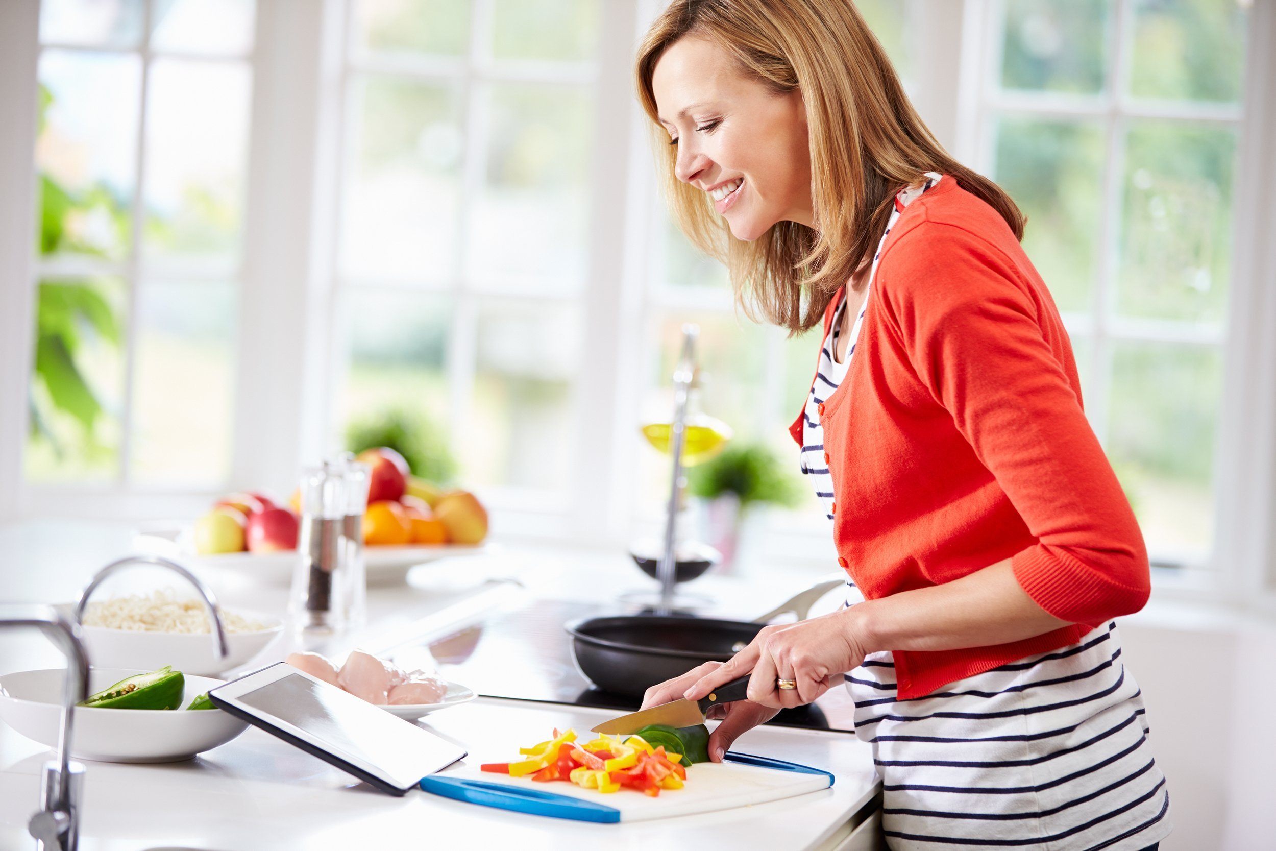 woman in kitchen following recipe on digital tablet