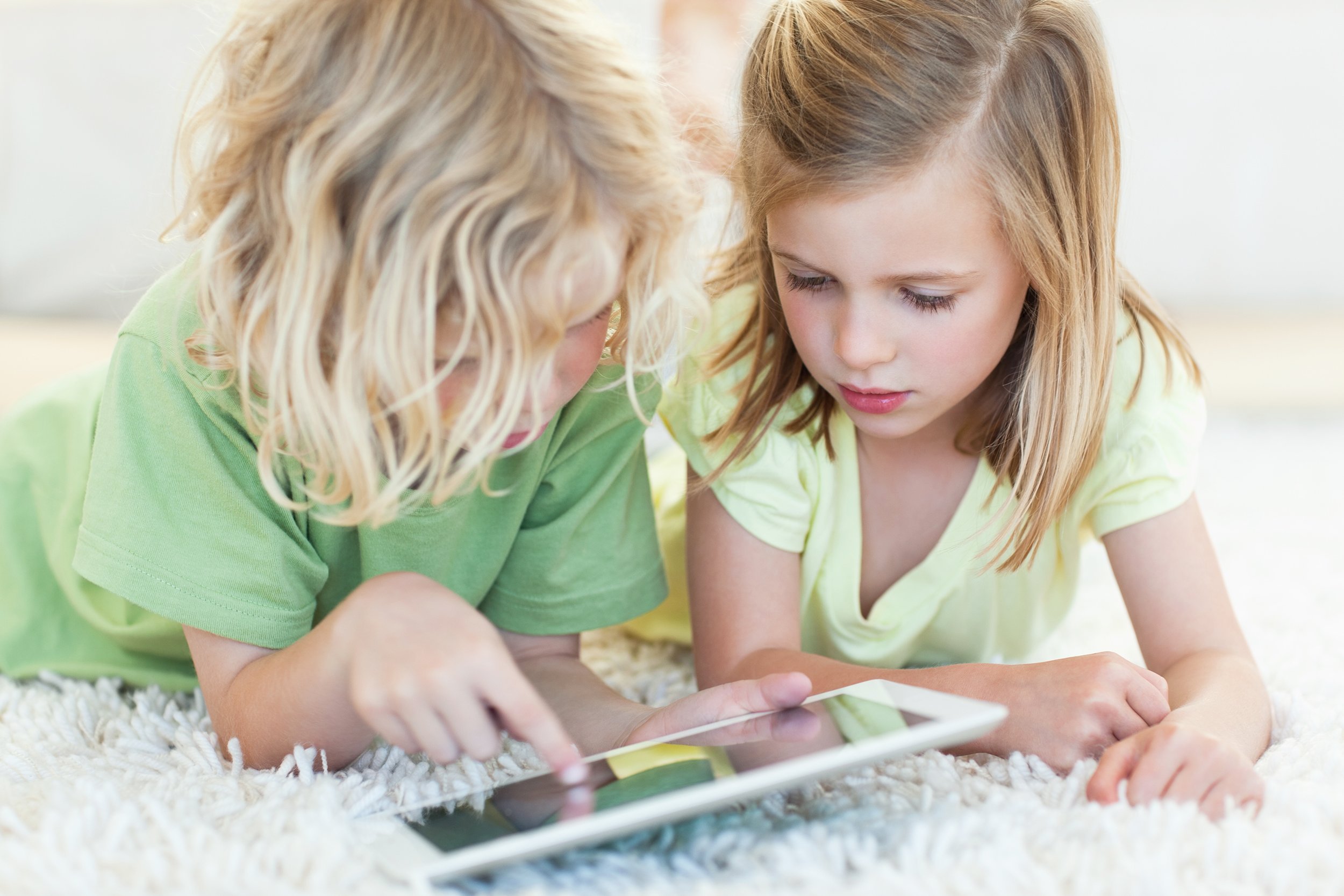 siblings together on the floor using tablet