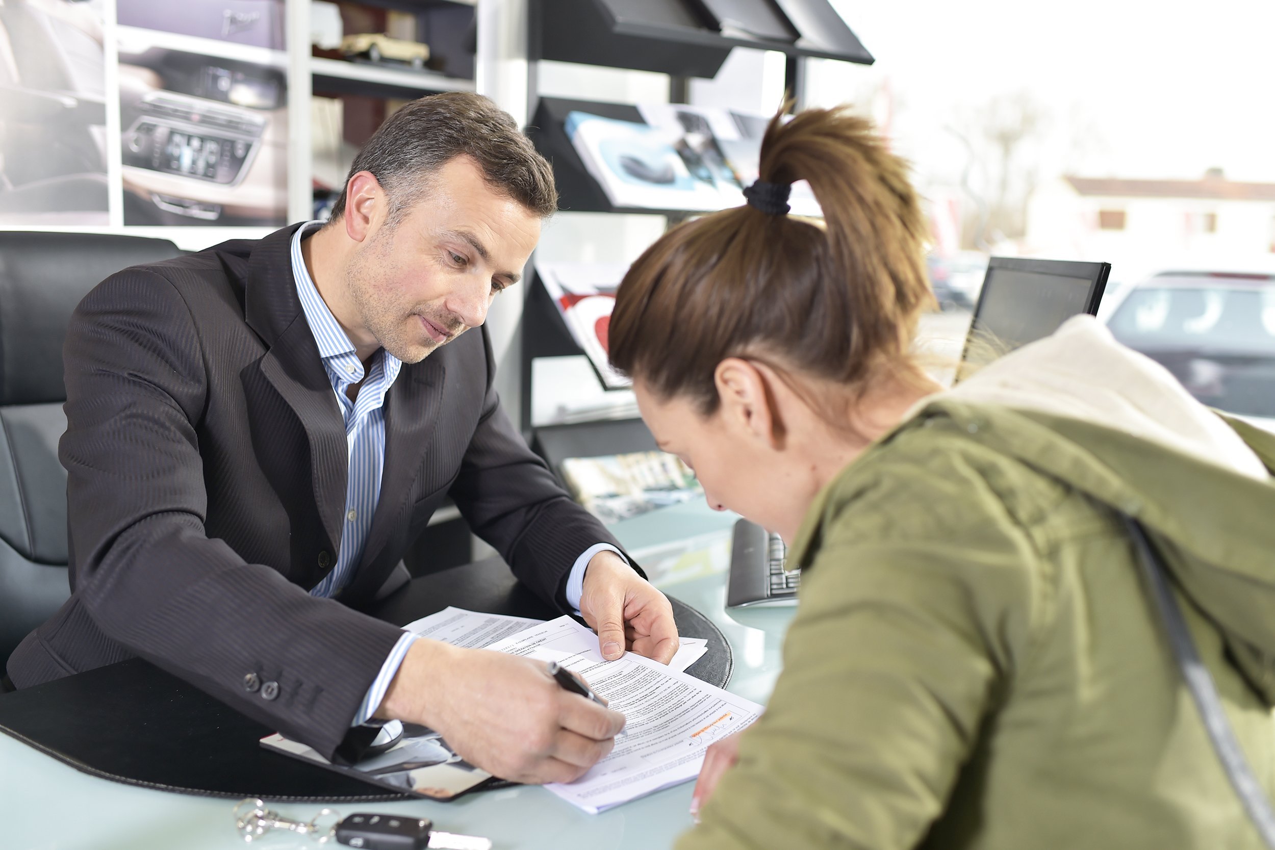 woman signing credit contract for car purchase