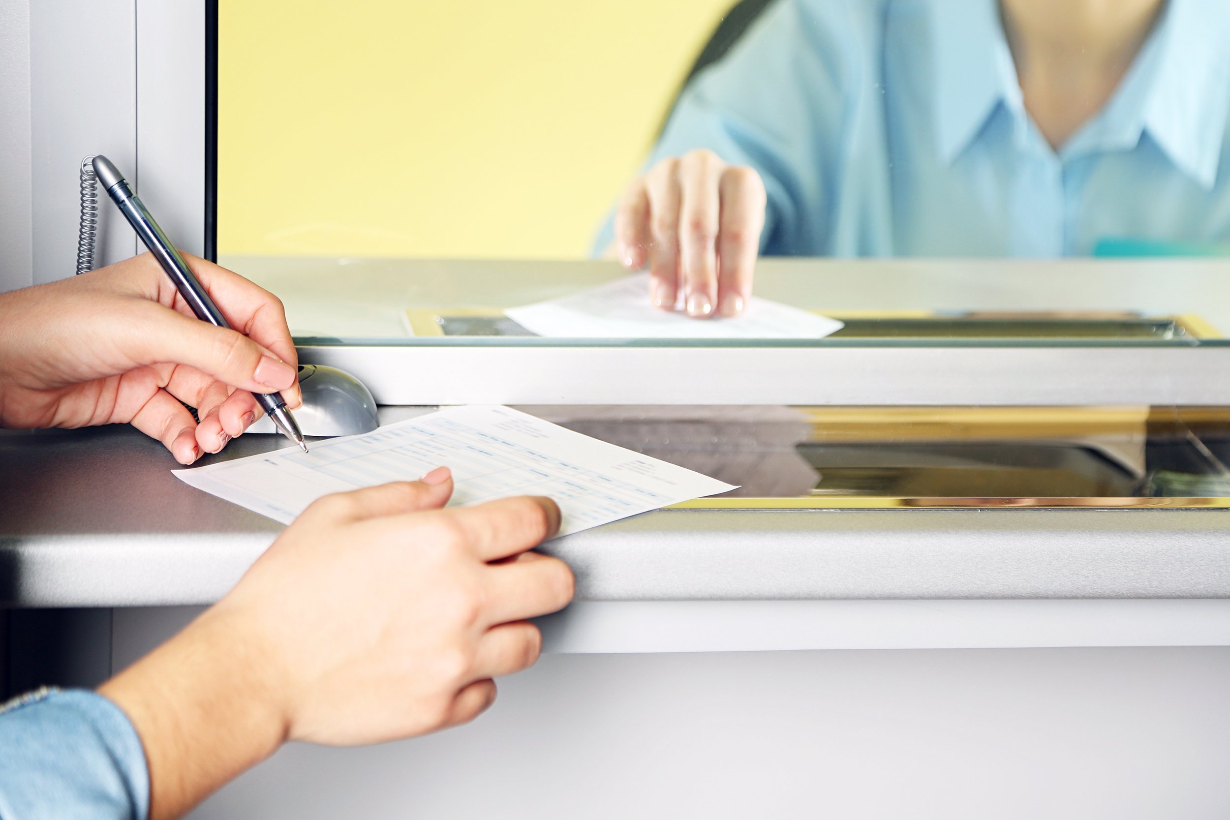 teller window with working cashier and female hands with claim check