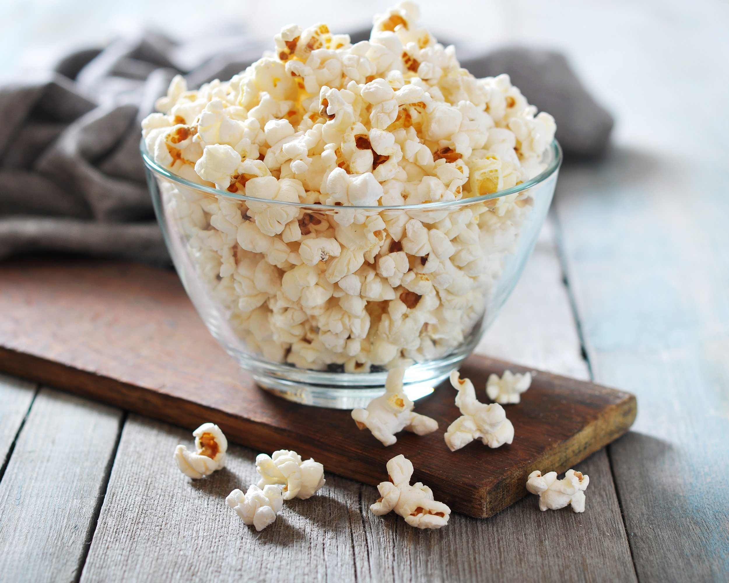 popcorn in glass bowl over wooden background