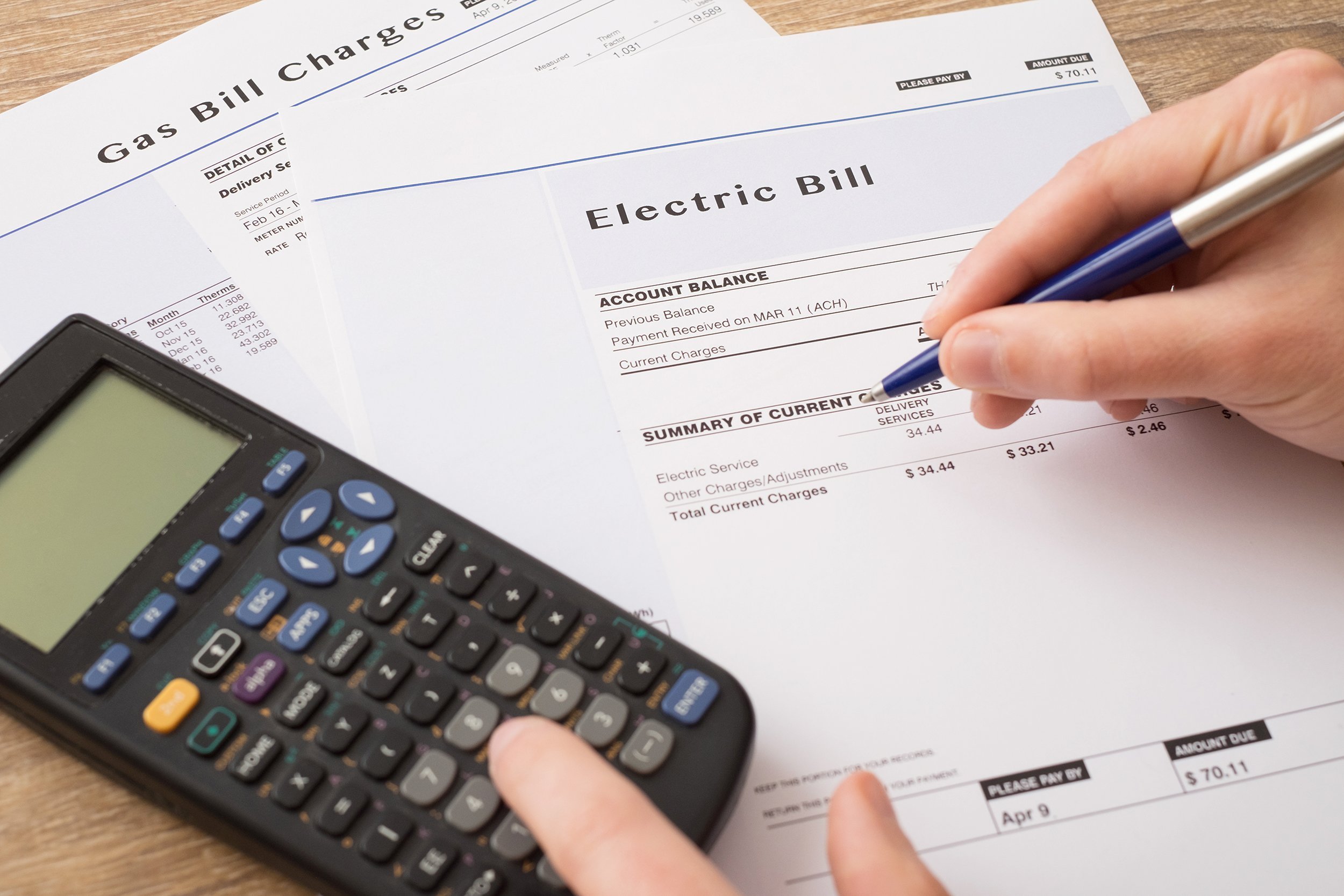hand and calculator on gas and electric bills