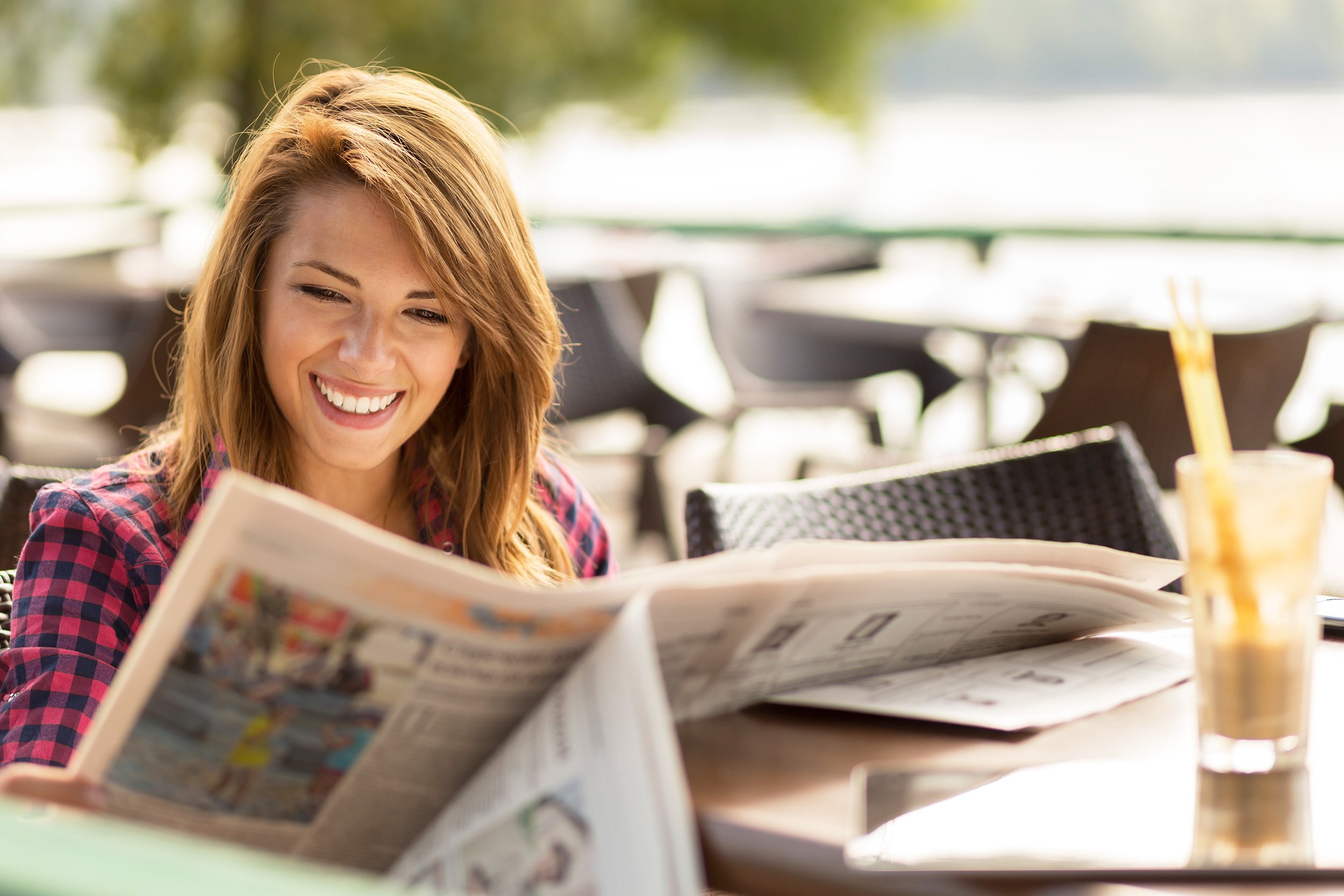 woman sitting in a cafe, drinking coffee and reading newspapers
