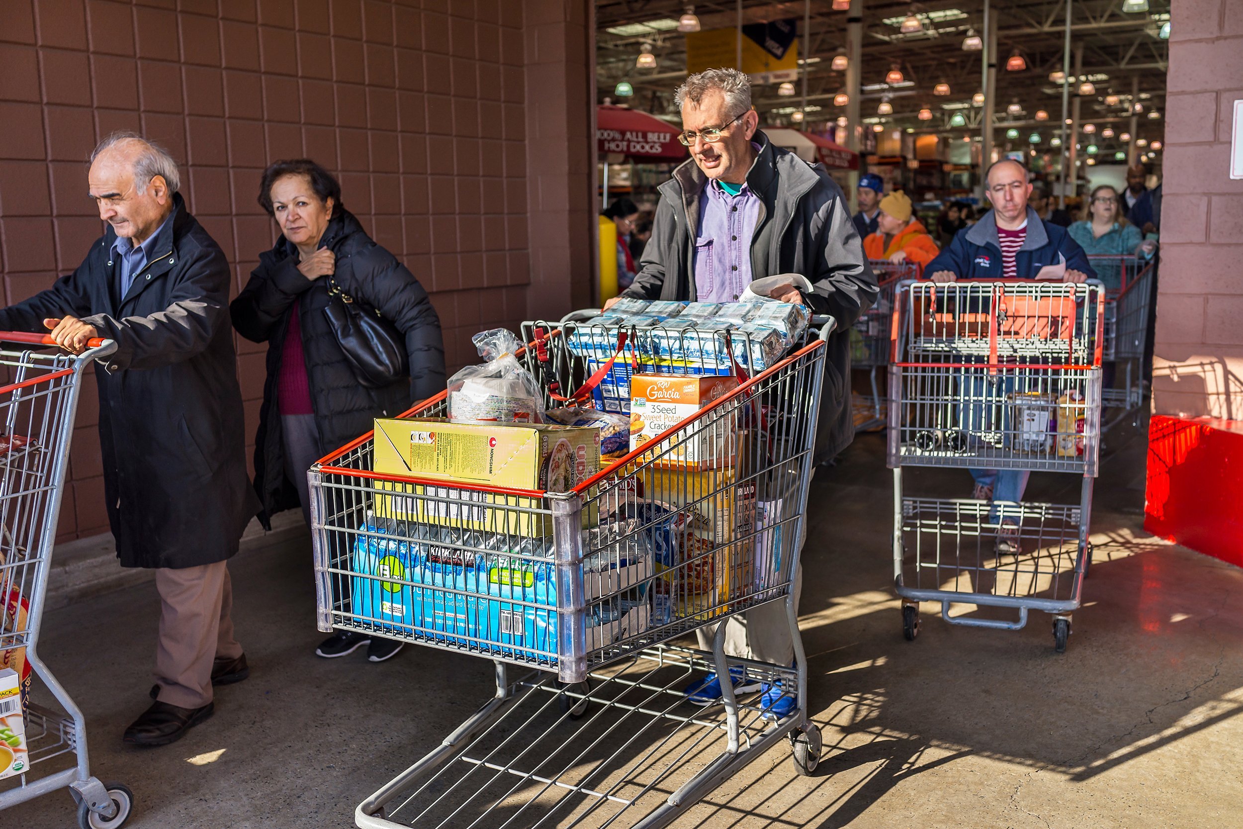people with shopping carts filled with groceries walking out of Costco store
