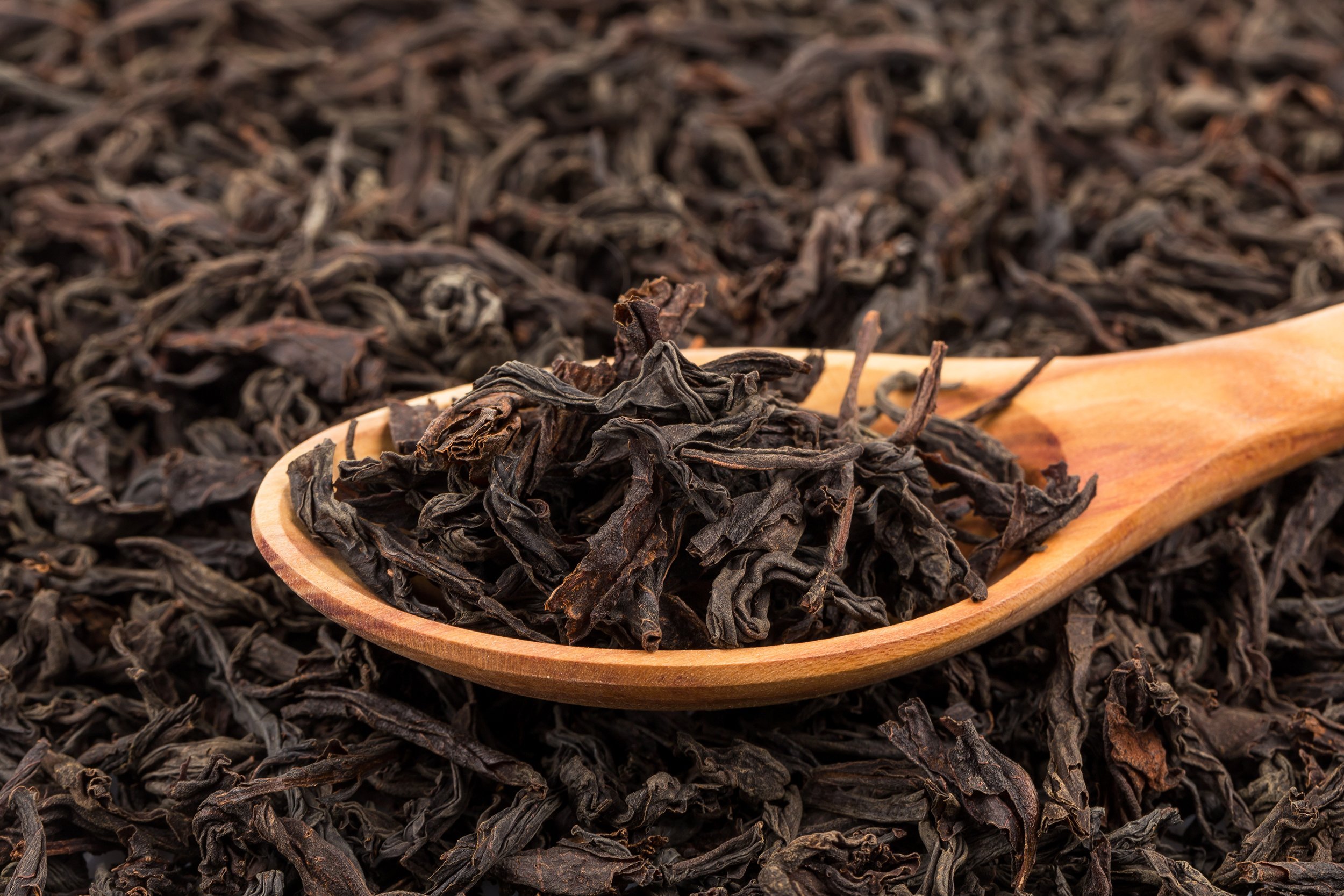 black tea in a spoon on a black tea background