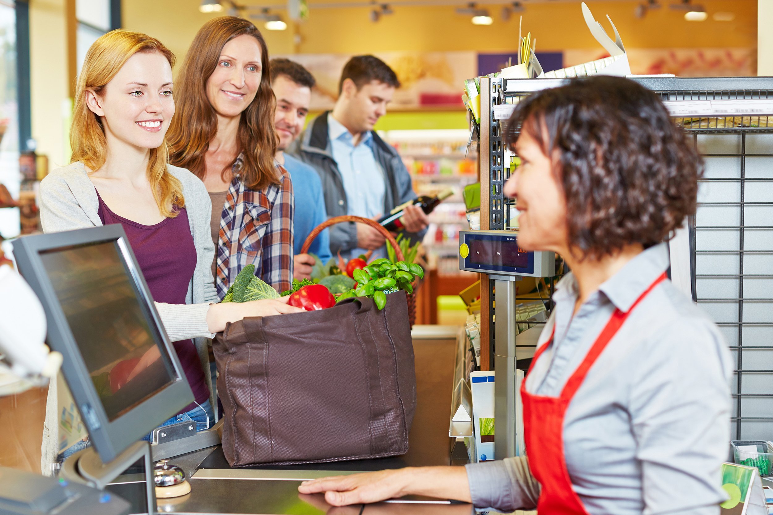woman with groceries waiting in line at the supermarket checkout