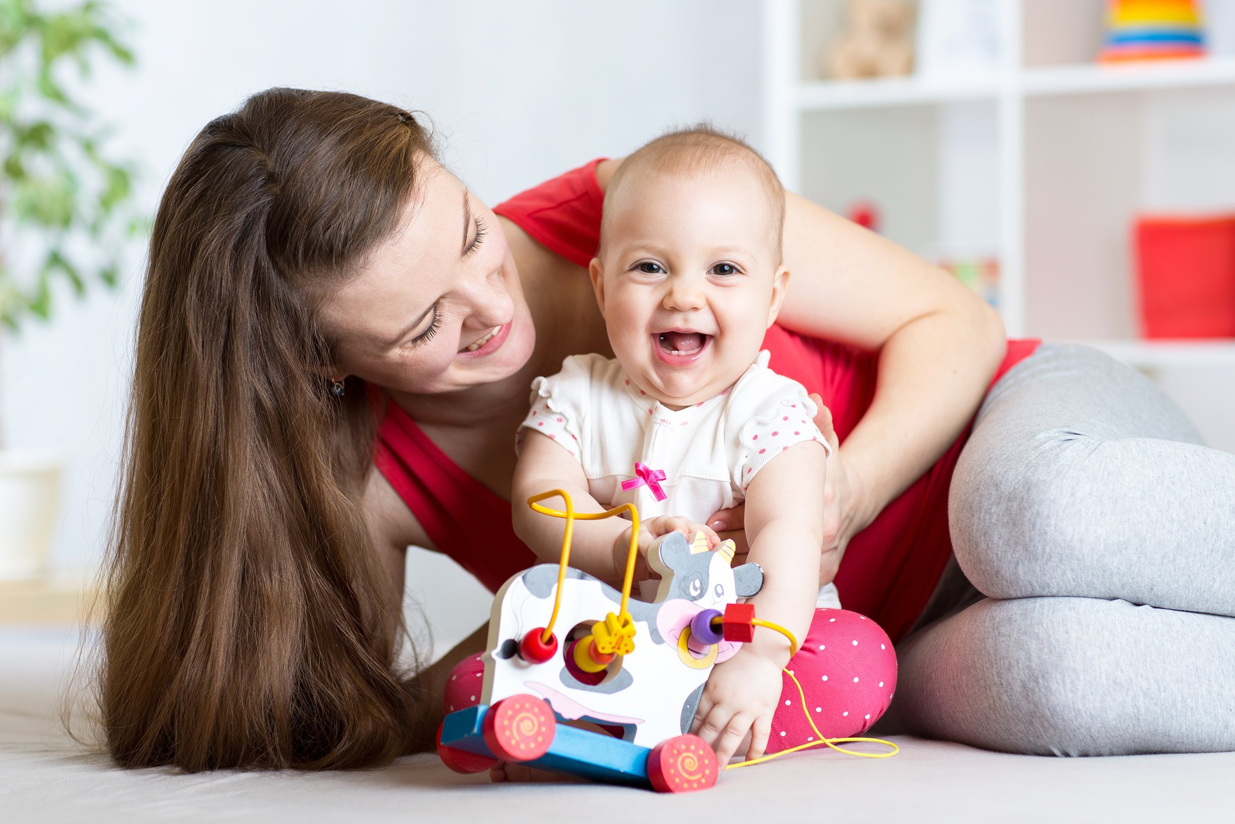 mother and baby girl playing with toy in living room