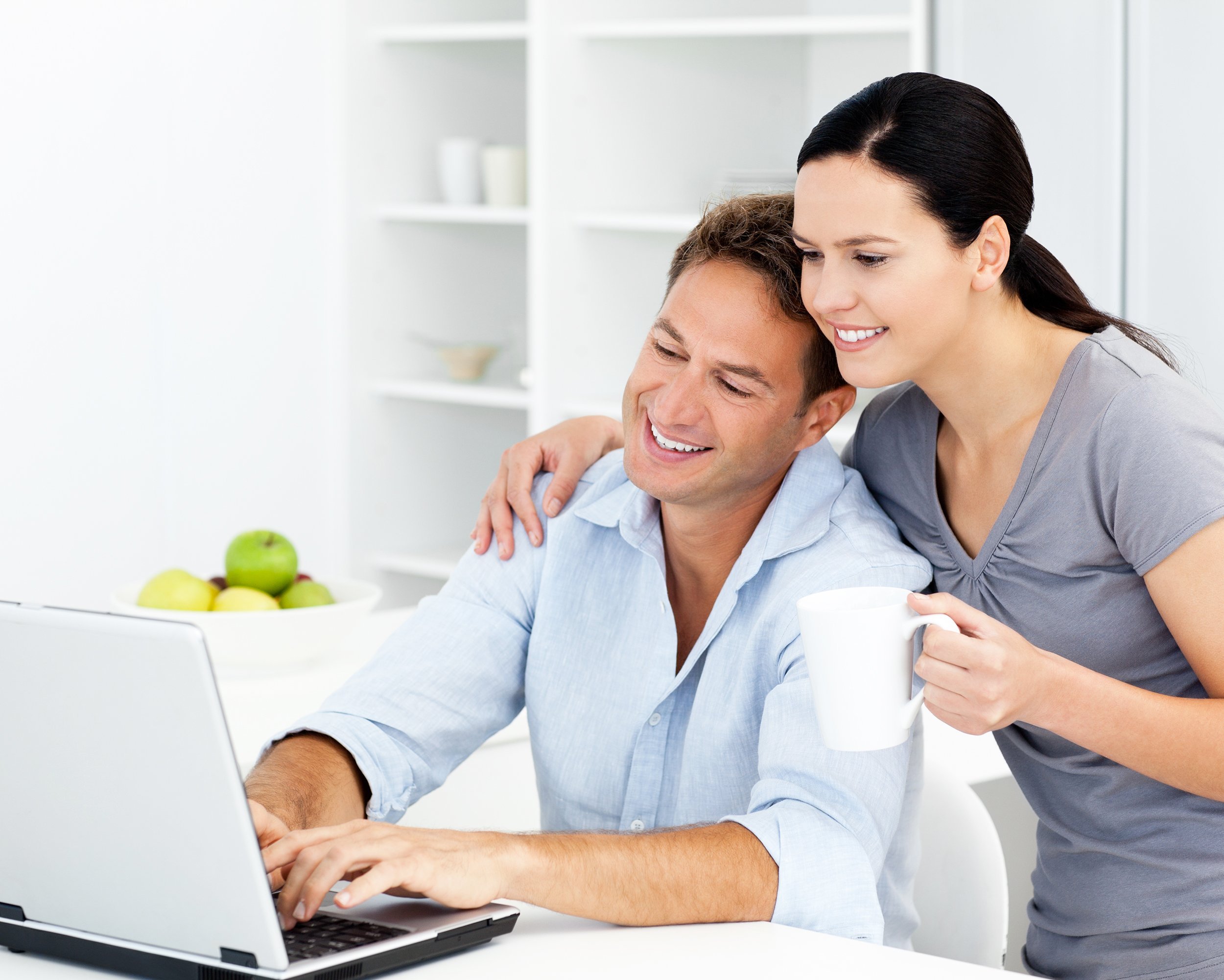 affectionate woman looking at her boyfriend working on the laptop in the kitchen