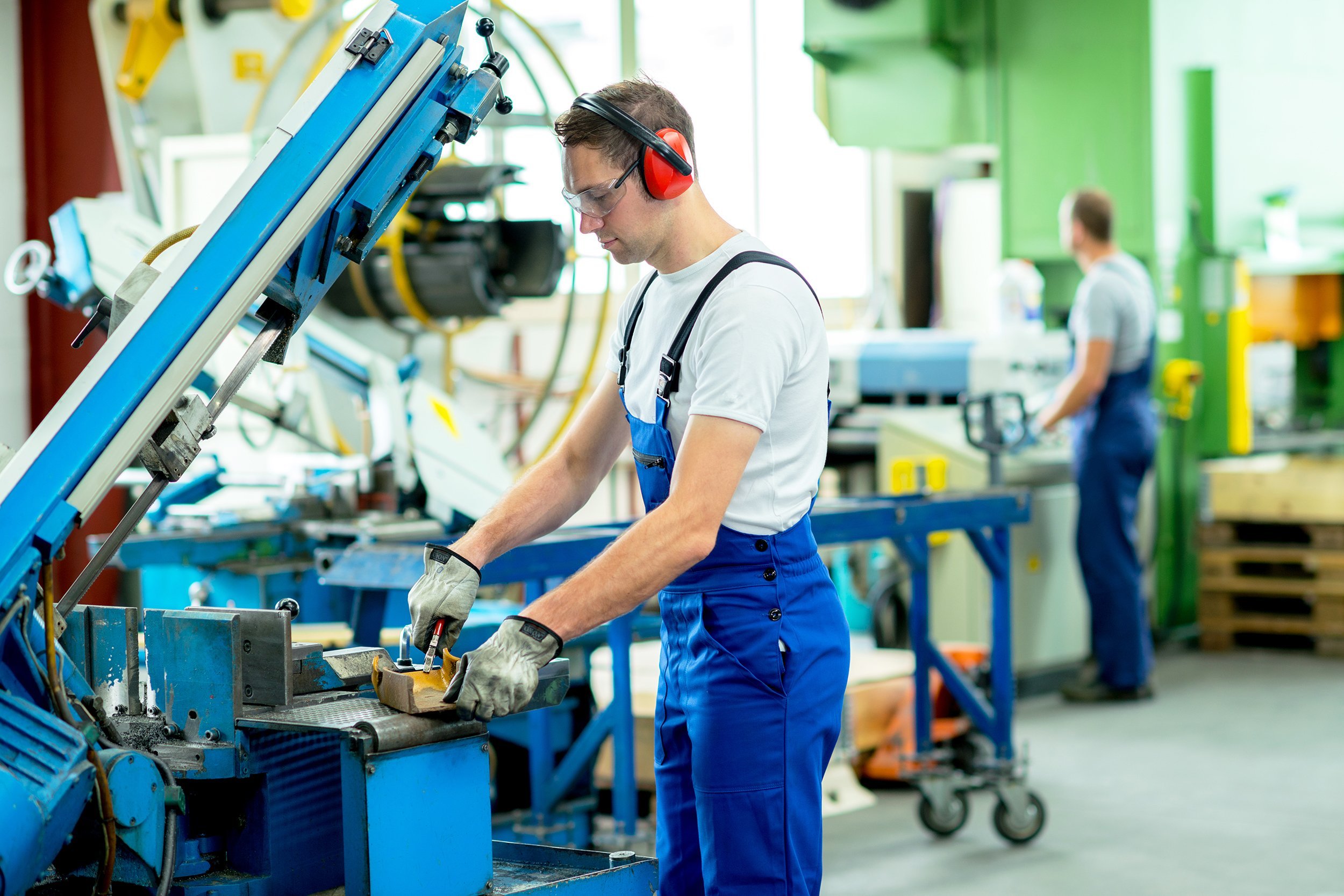 worker in protective clothing in factory using machine