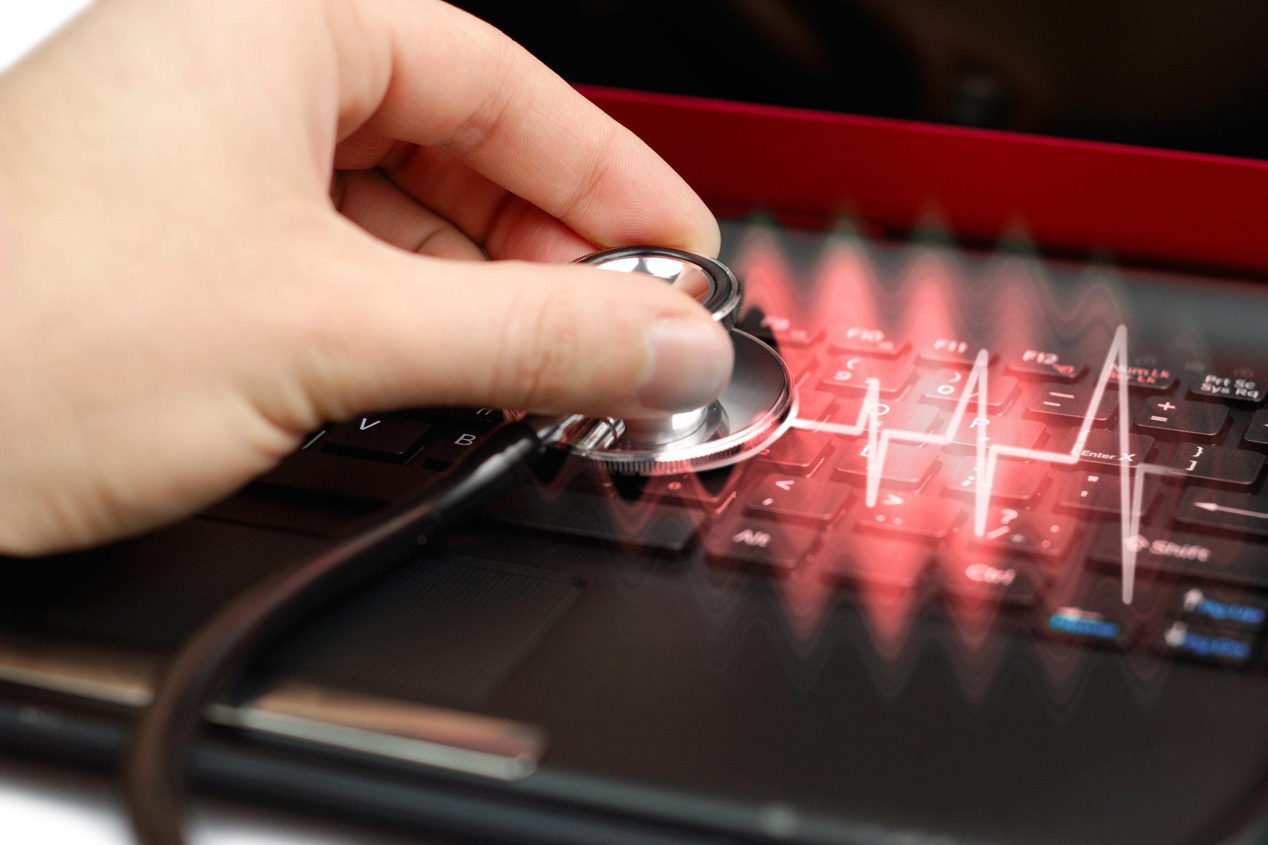 male hand with stethoscope over black keyboard of laptop