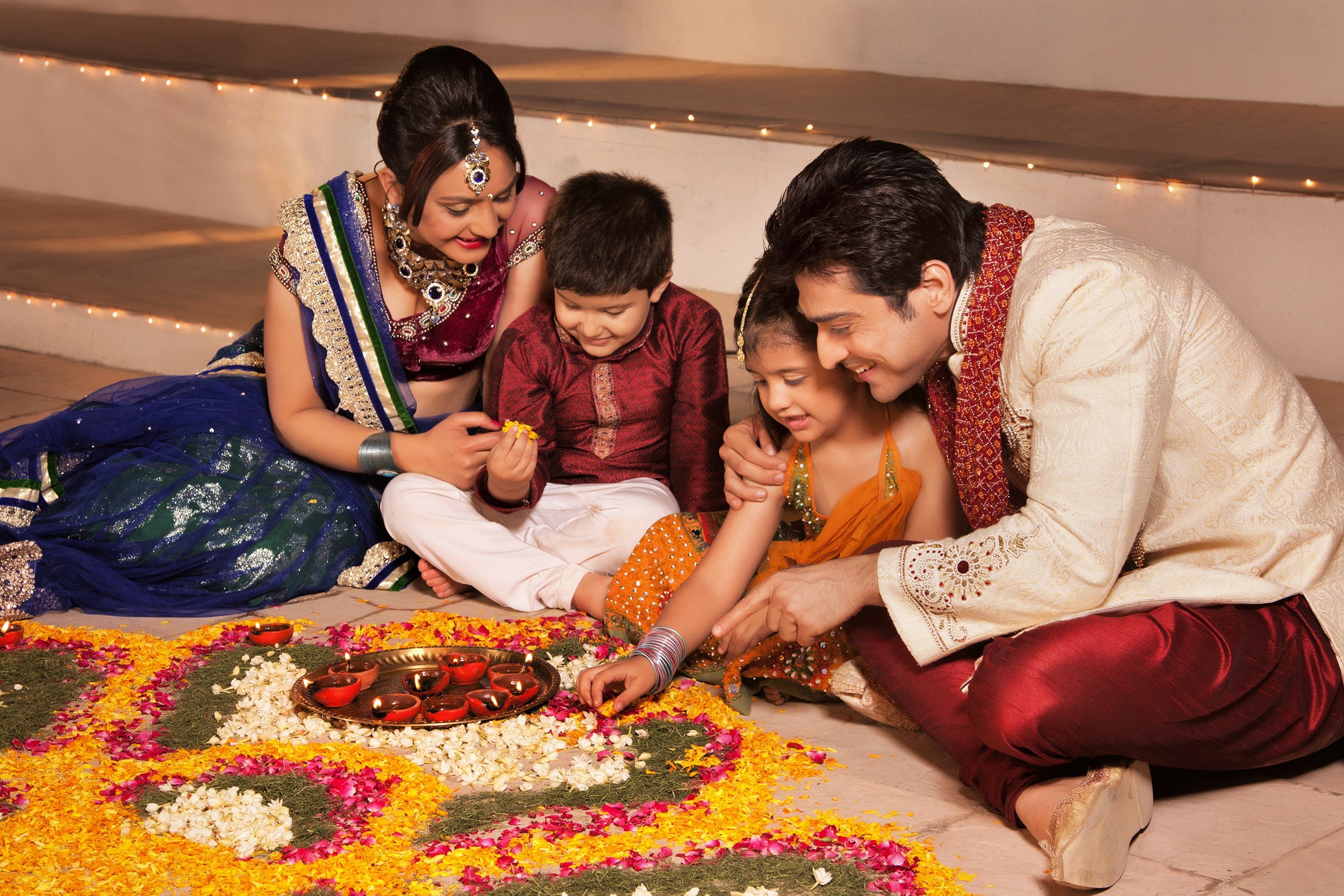 family arranging diyas on rangoli during Diwali
