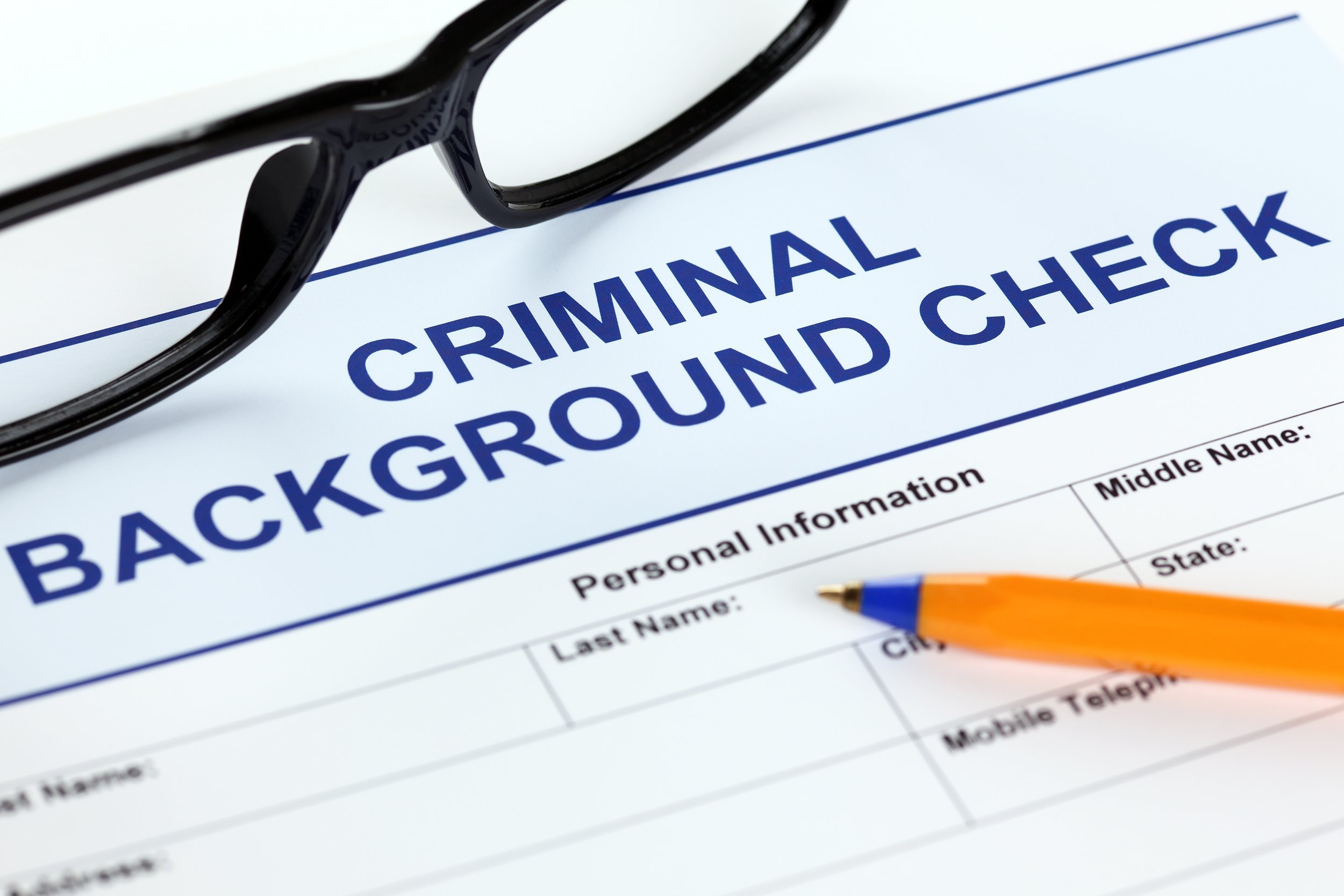 criminal background check application form with glasses and ballpoint pen