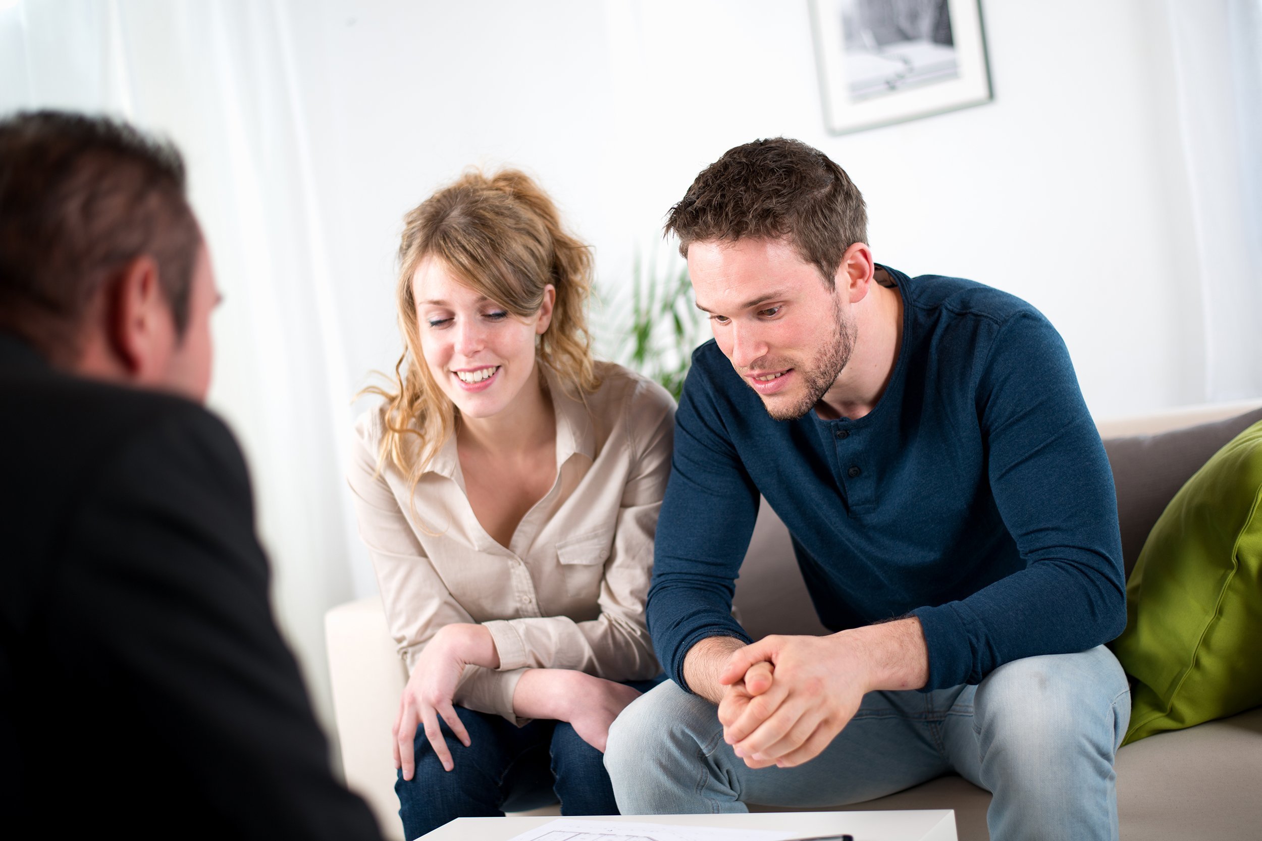 cheerful young couple with salesman at home
