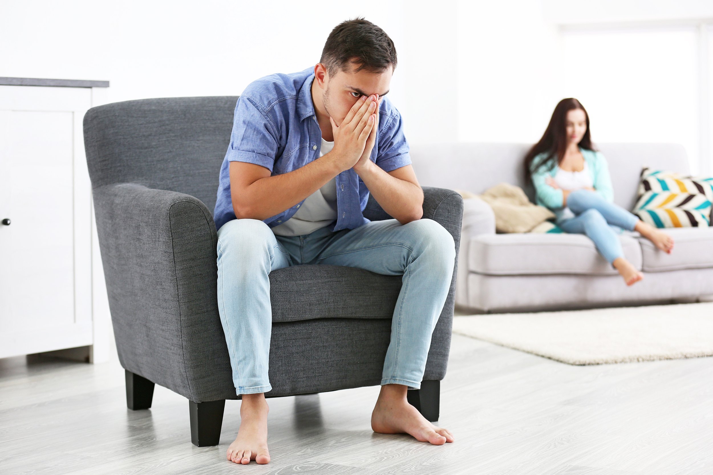 young couple sitting separately in quarrel at home
