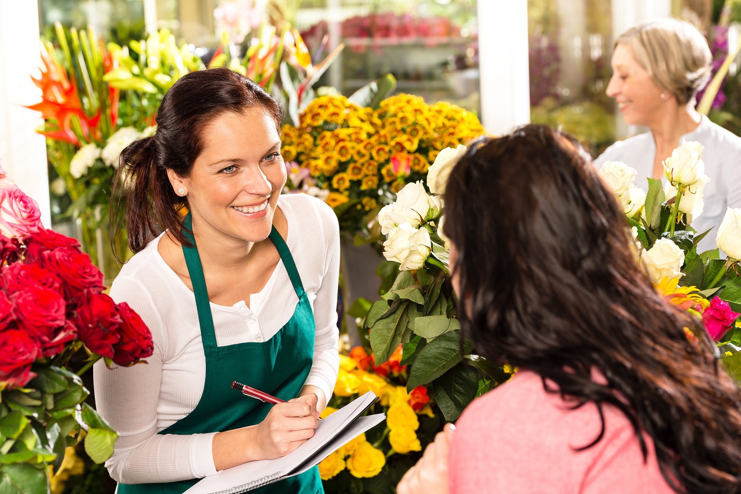 happy florist writing flower shop talking customer woman