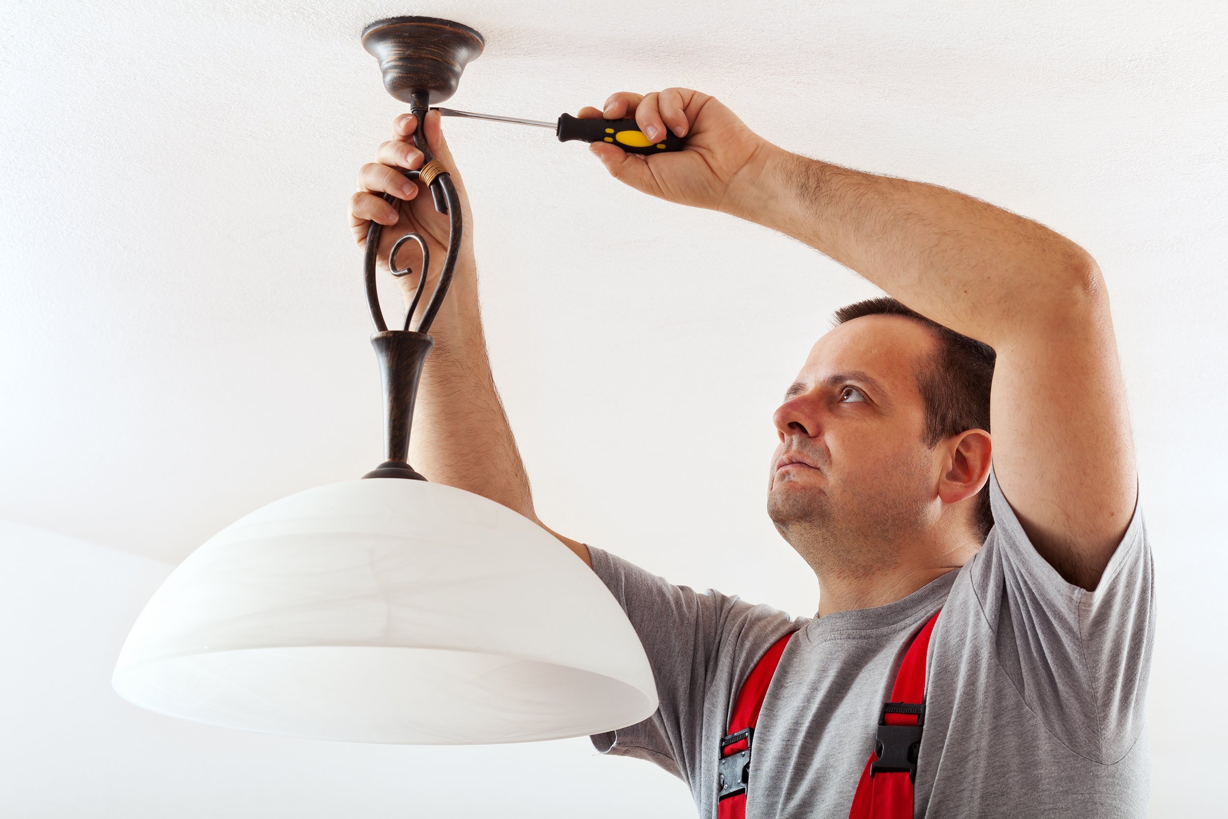 electrician mounting and installing the wires of a ceiling lamp