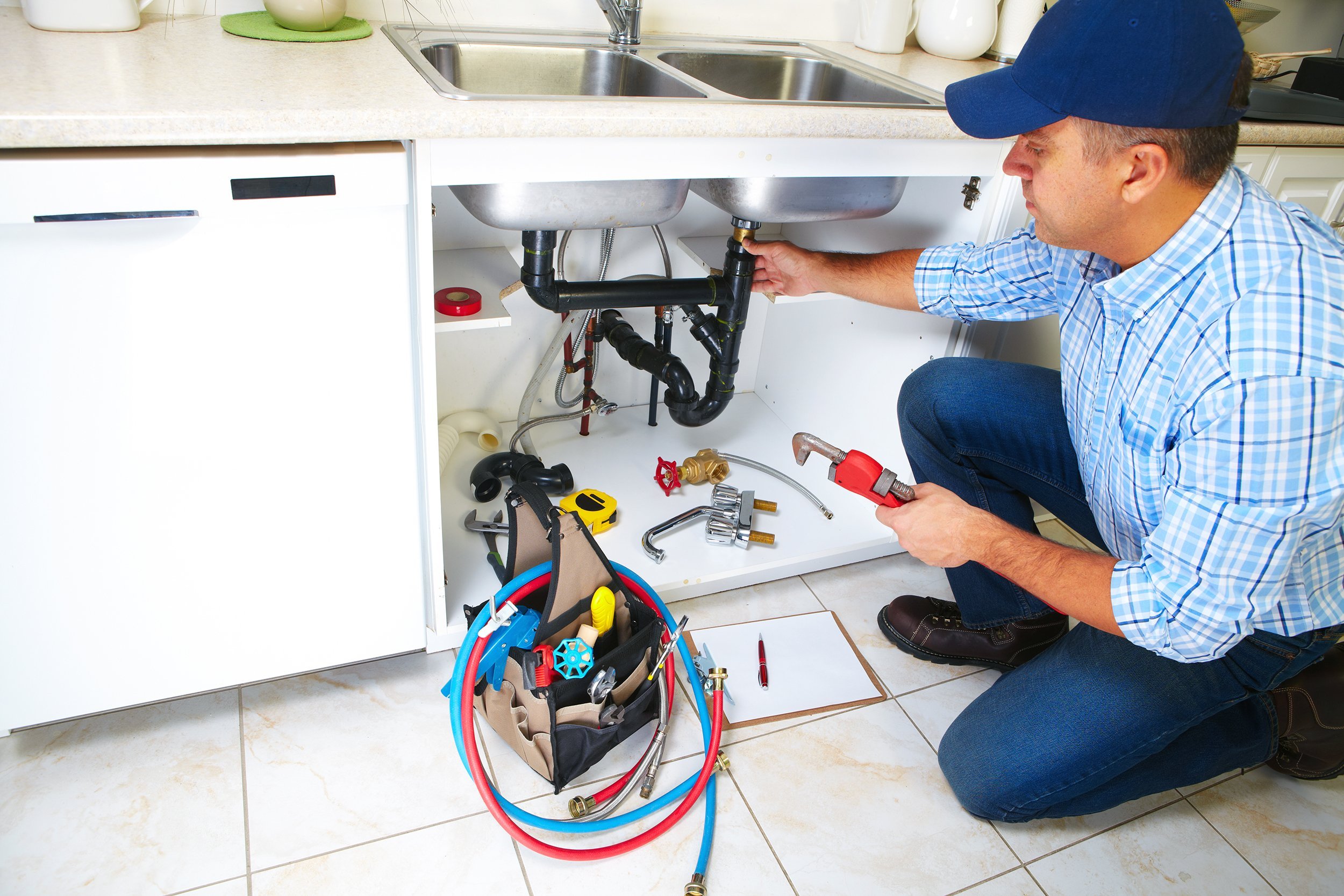 plumber with plumbing tools fixing kitchen sink