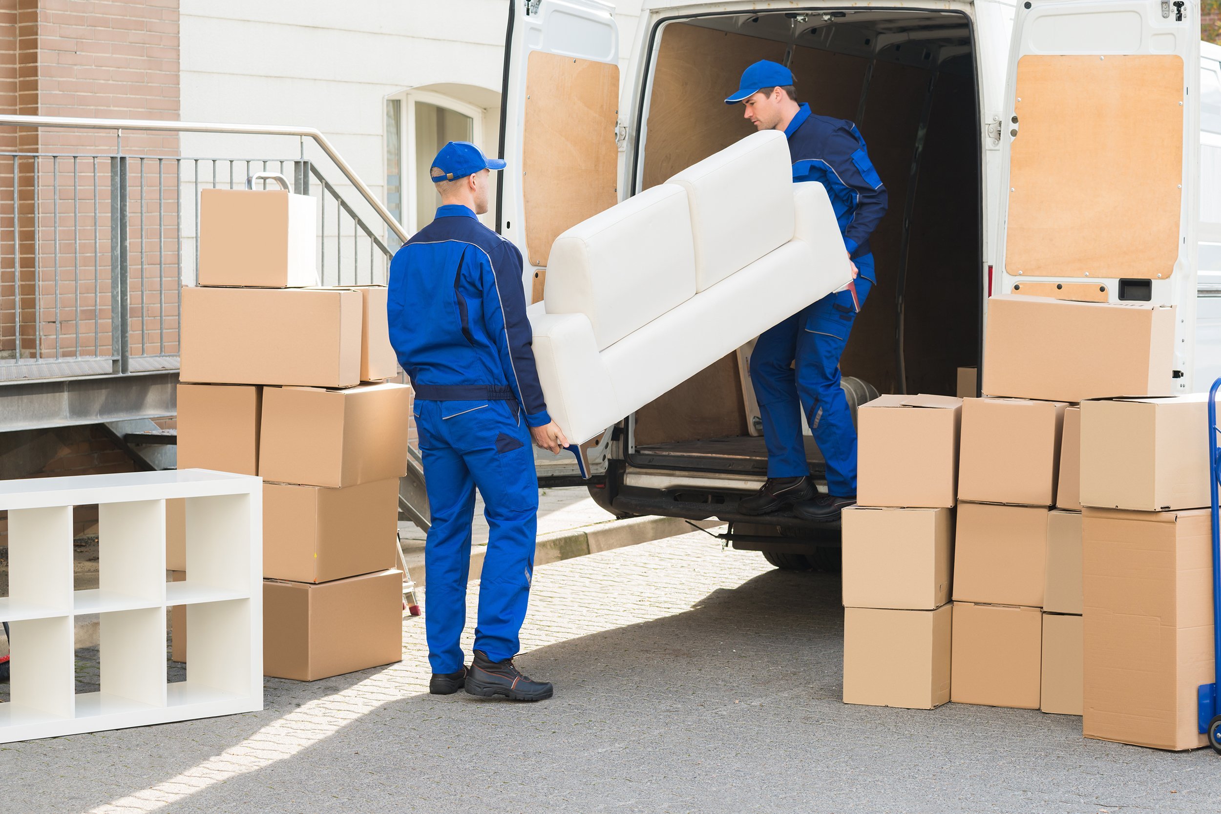 young male movers unloading sofa from truck on street
