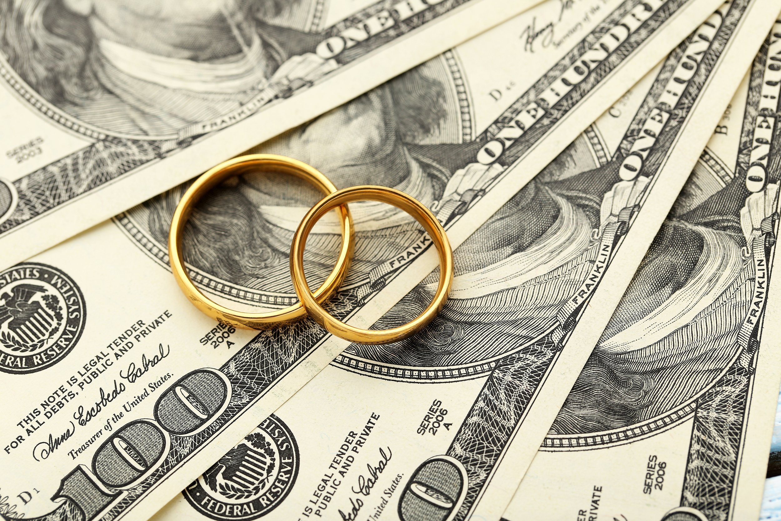 golden wedding rings on one hundred dollars bill background